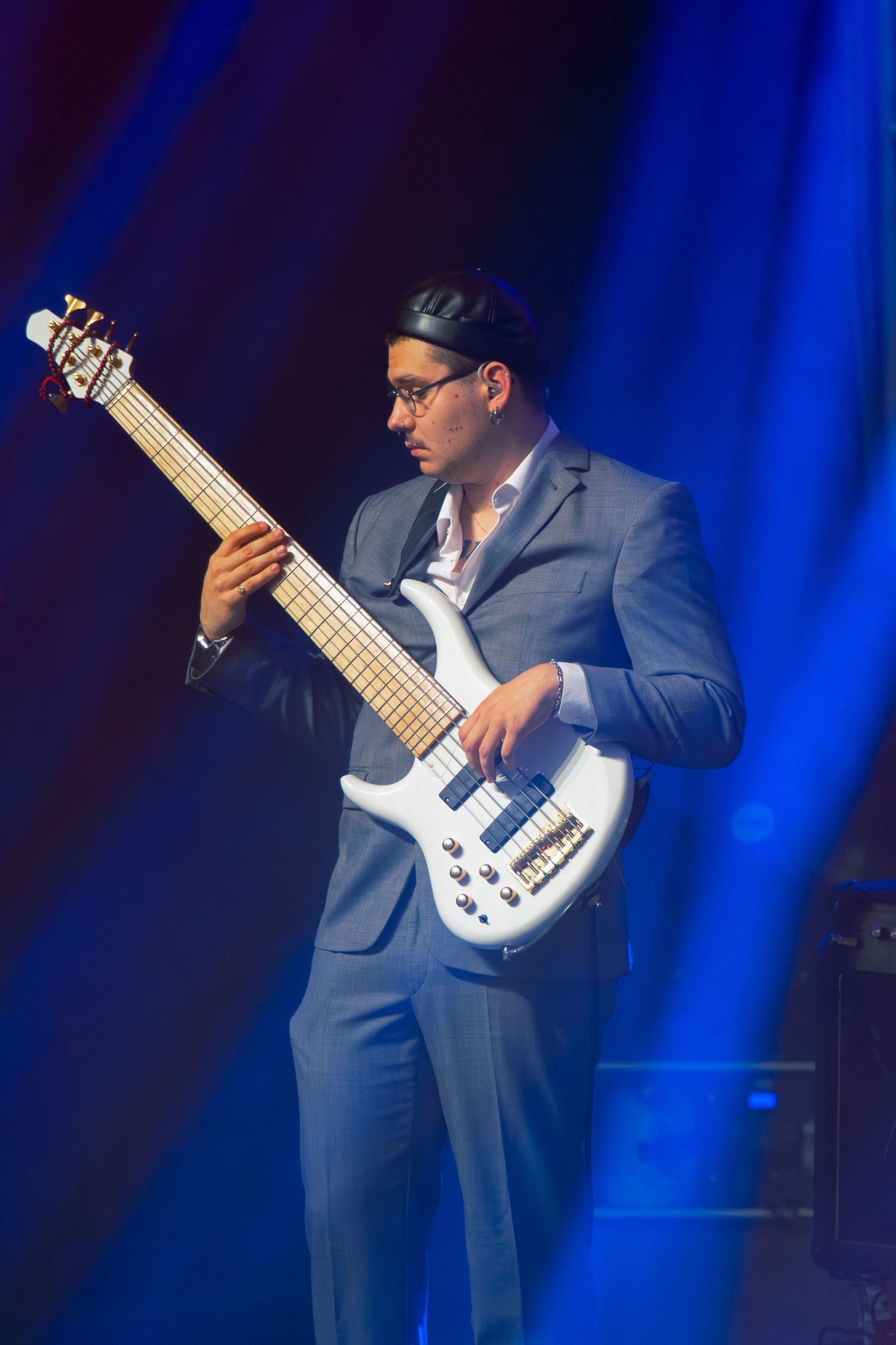 zenész szürke öltönyben basszusgitáron játszik kék fények alatt