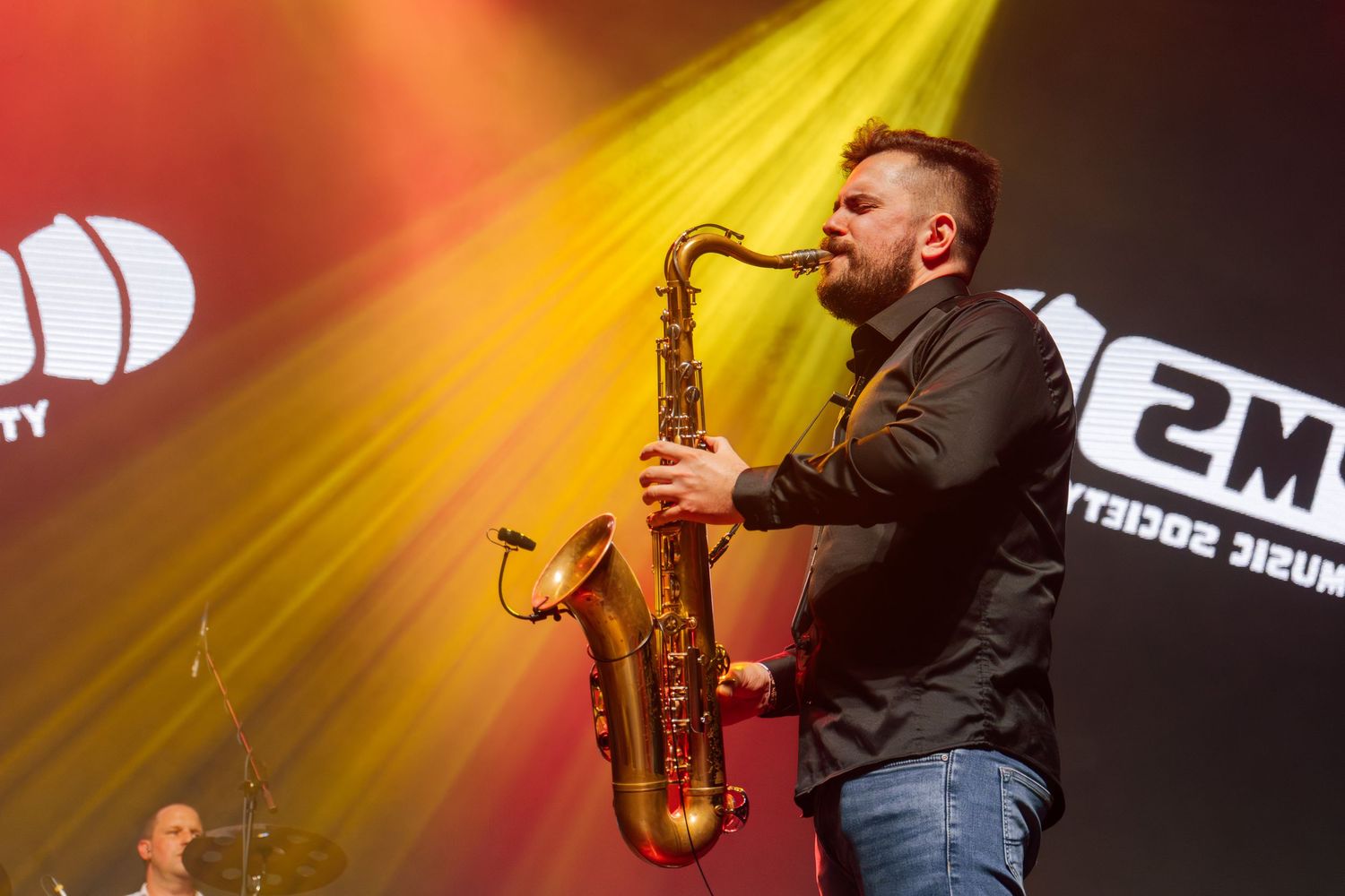 zenész arany szaxofonon játszik színpadon