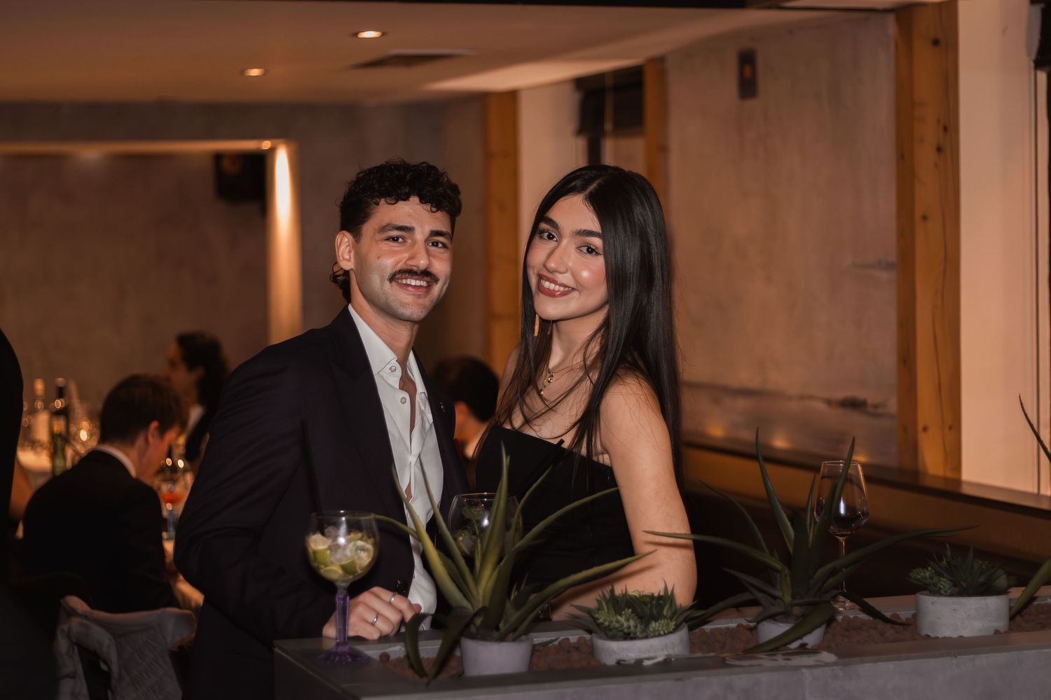 elegánsan öltözött pár áll egy étteremben borral és dekorációval az asztalon