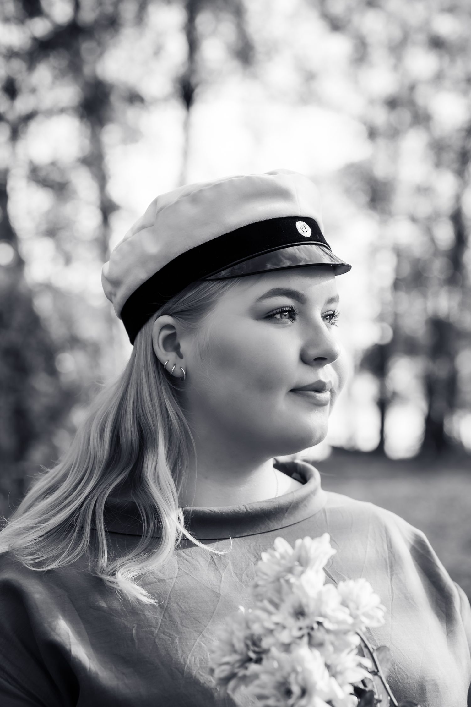 Mustavalkoinen ylioppilaskuva vaaleasta nuoresta naisesta, hän pitelee kukkia käsissä.