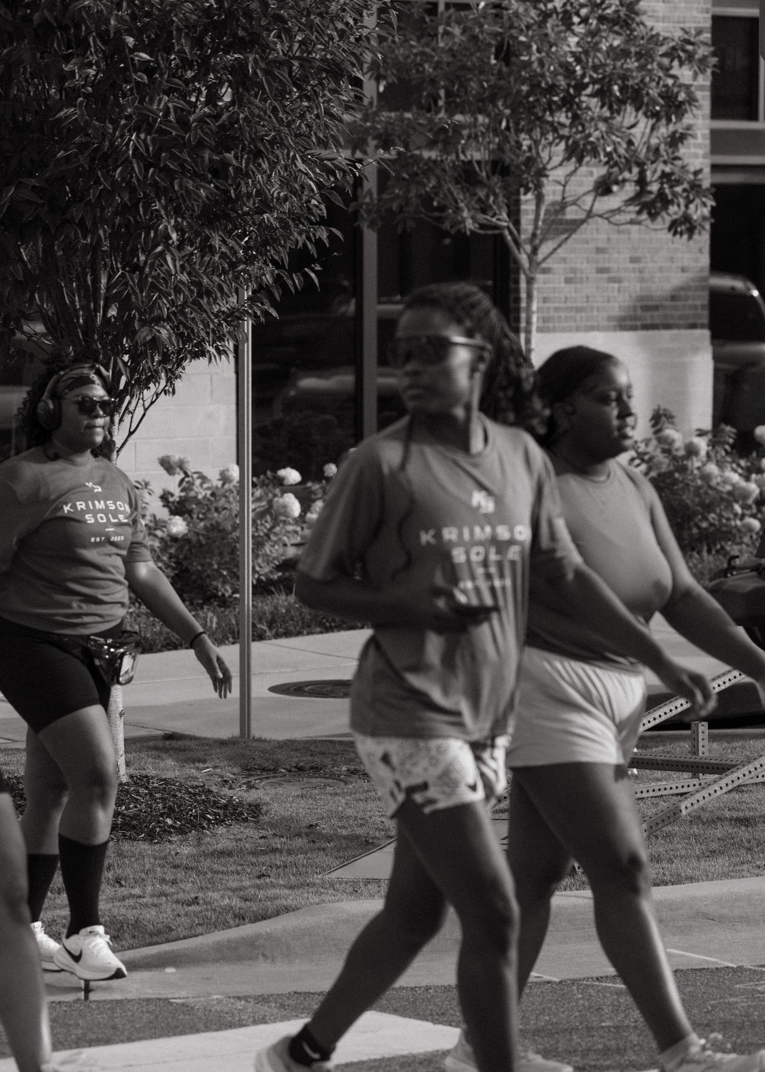 Black and white photo of women wearing Krimson Sole shirts walking outdoors during a group run.
