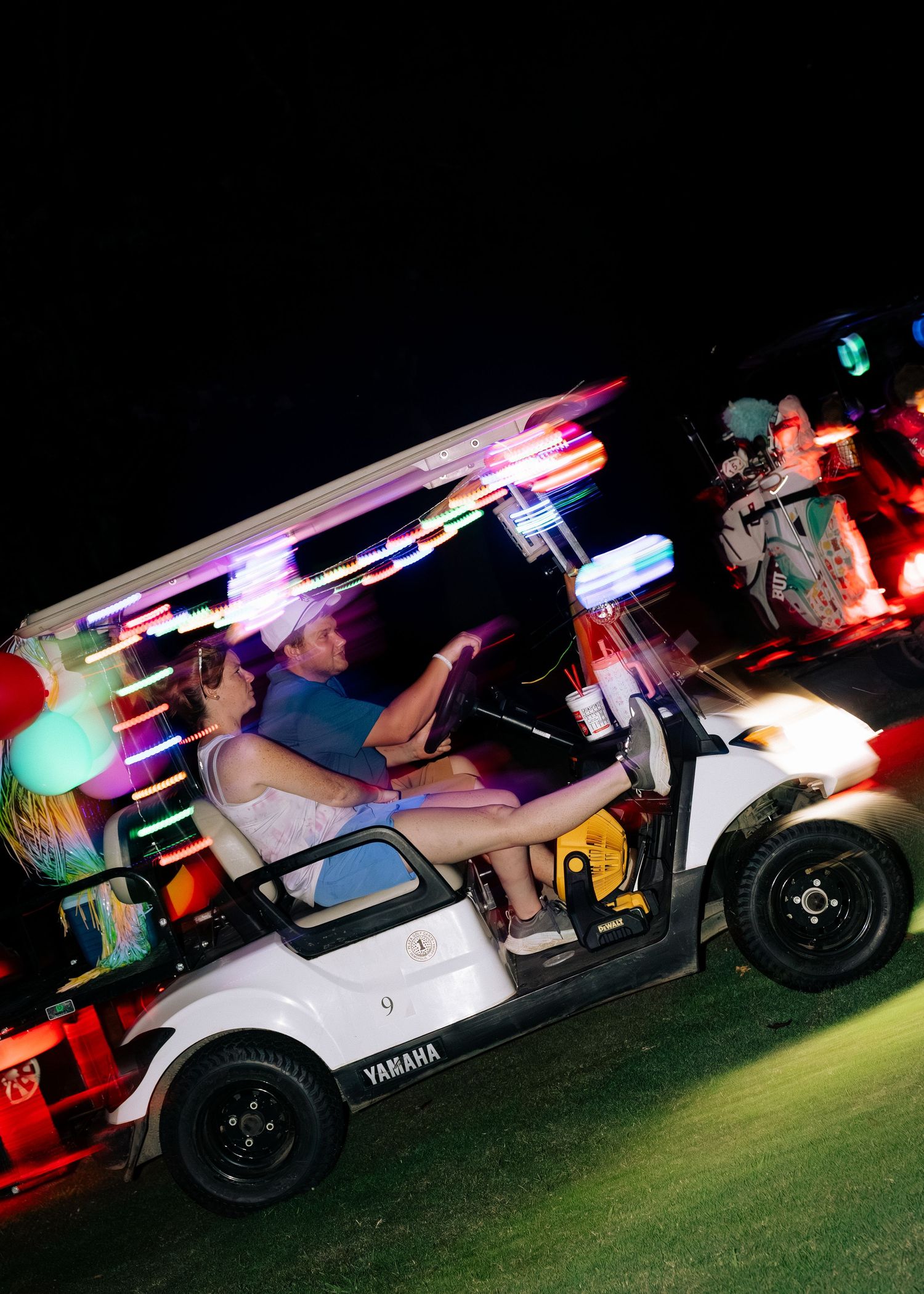 Colorfully lit Yamaha golf cart with motion blur captured during a festive night golf event.