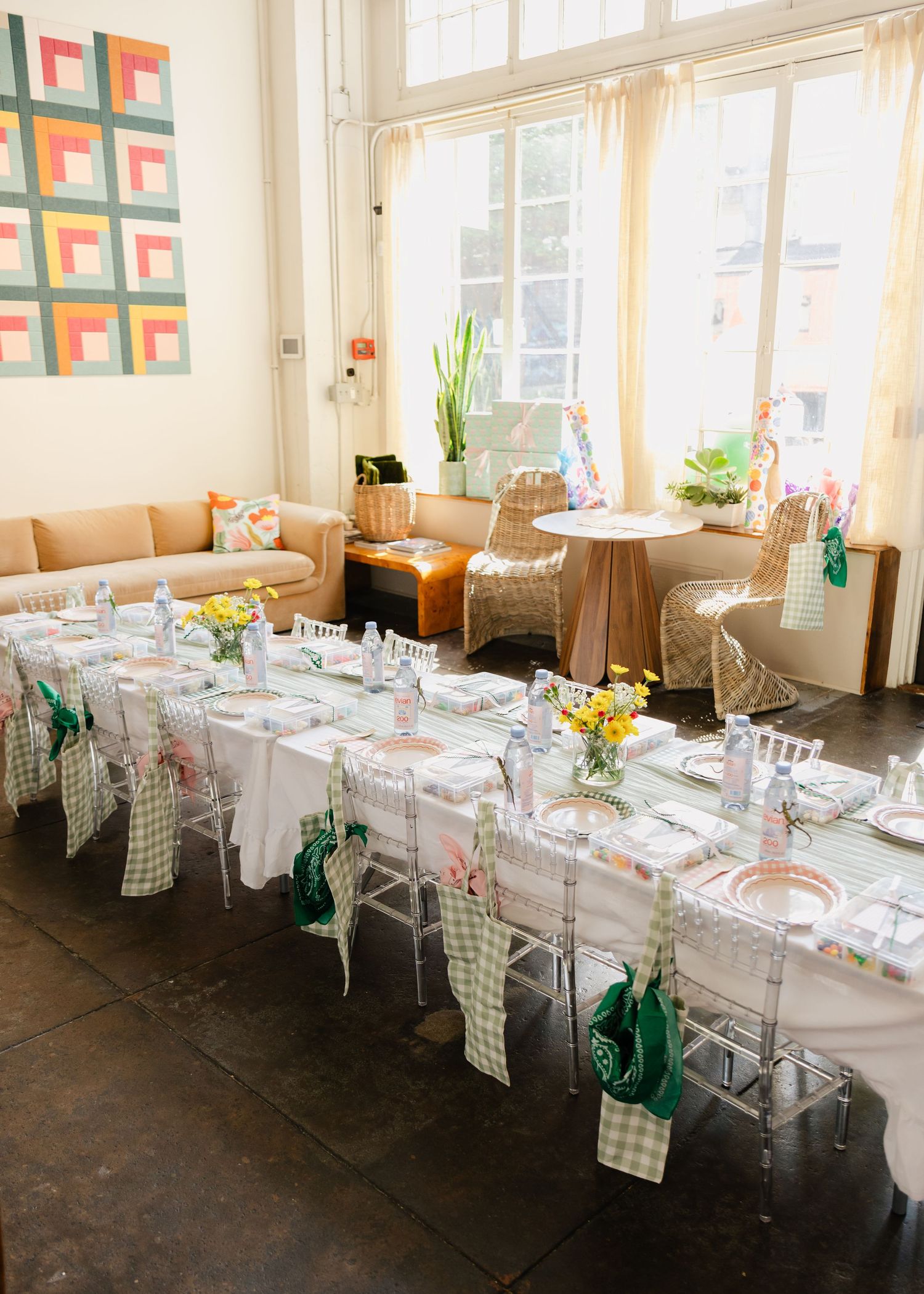 Children's birthday party table with gingham chair sashes, yellow flowers, and clear chiavari chairs.