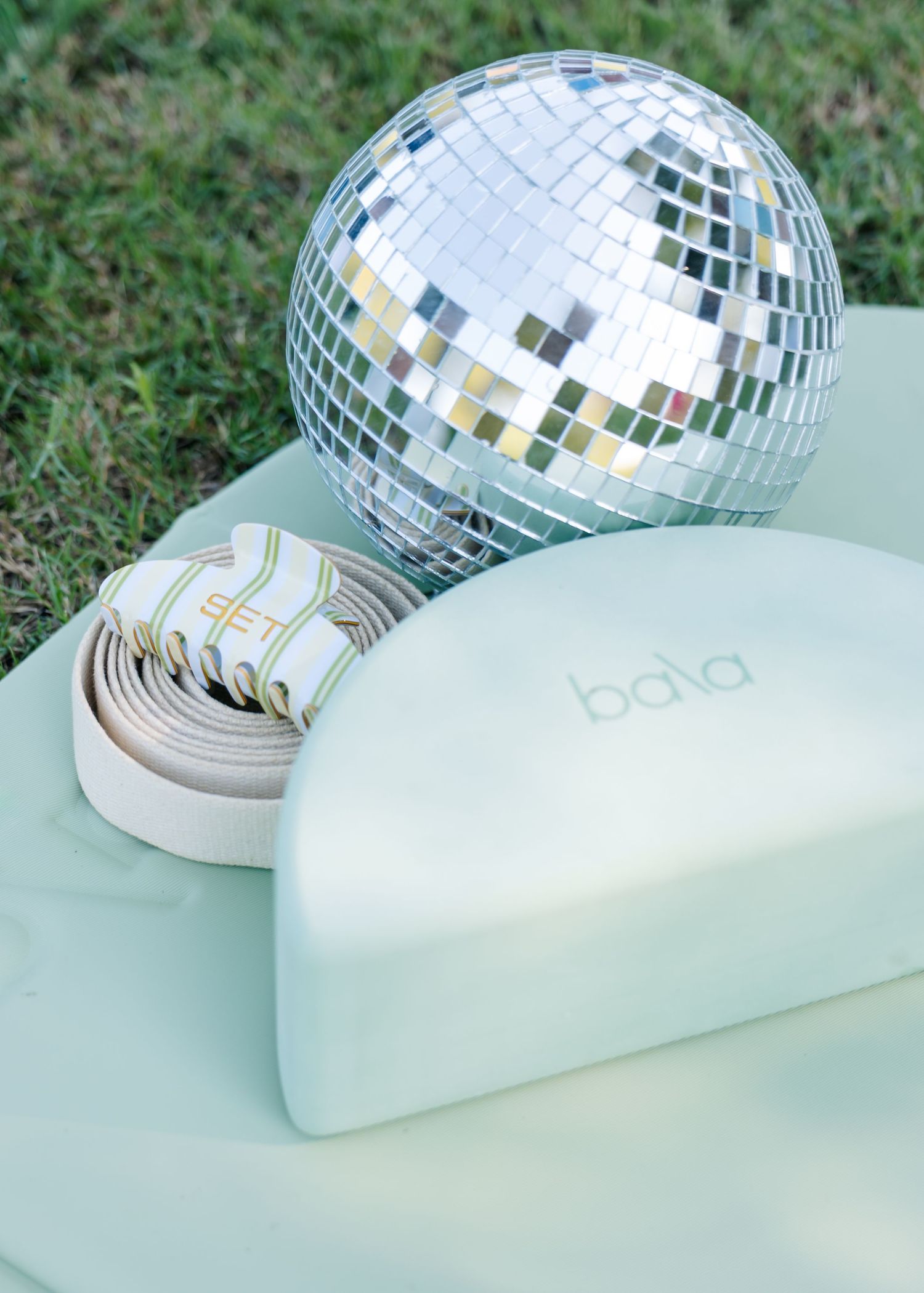 Bala brand fitness equipment with resistance bands and disco ball on a mint green yoga mat.