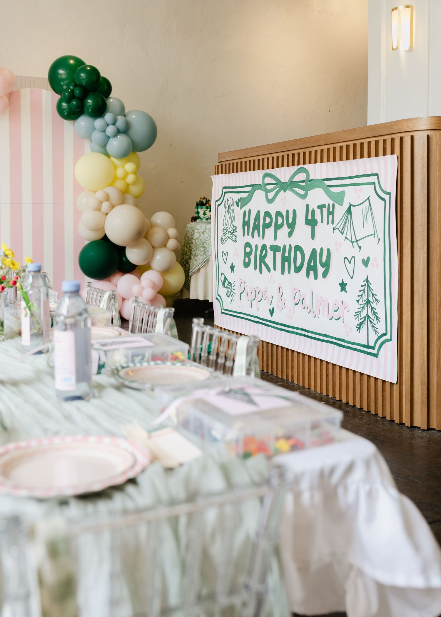 Happy 4th Birthday Pippa and Palmer party table setup with balloon garland and decorative banner.