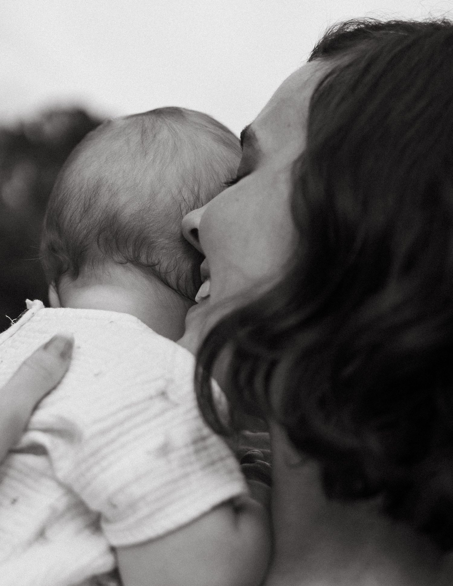 Tender black and white photo of a mother gently kissing her newborn baby.