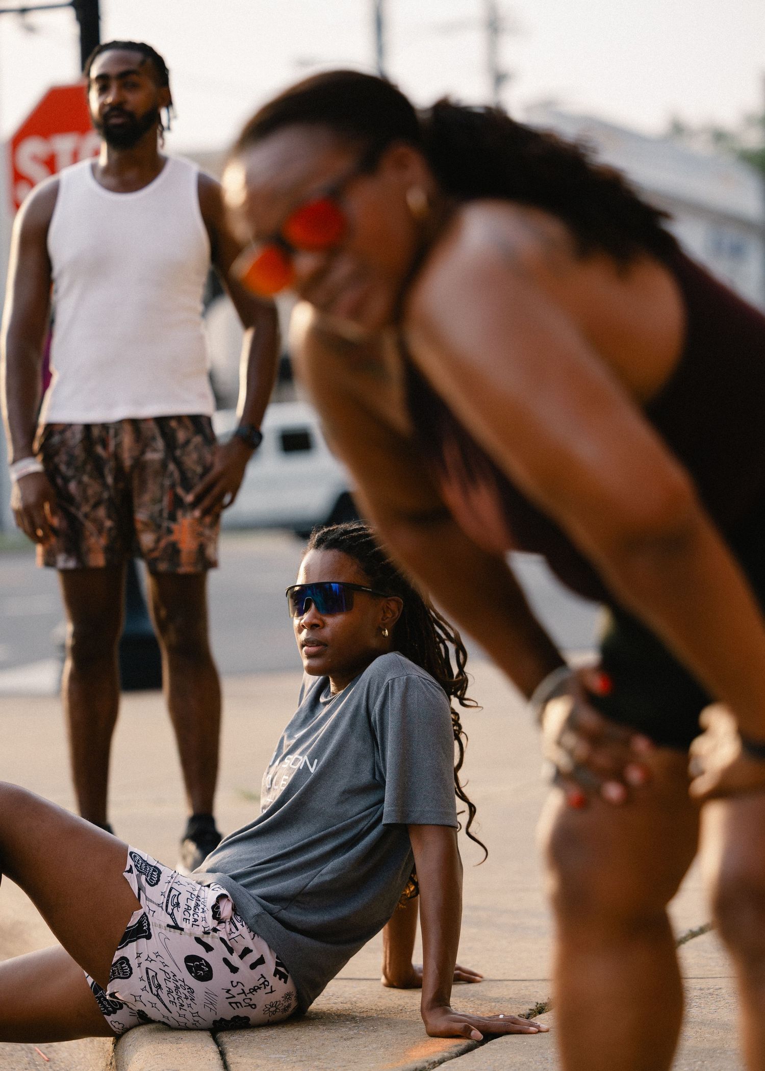 Group of people resting on a street corner after a run at golden hour.