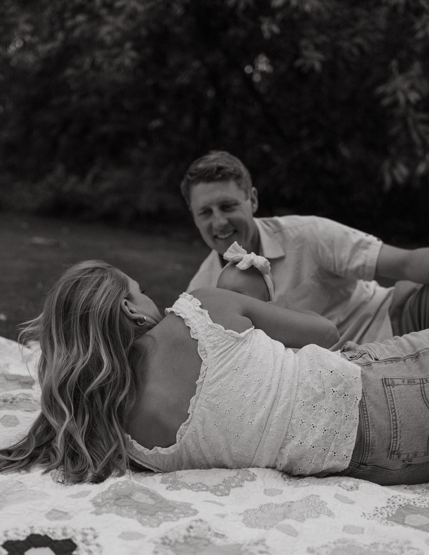 Black and white photo of couple relaxing on picnic blanket in garden.