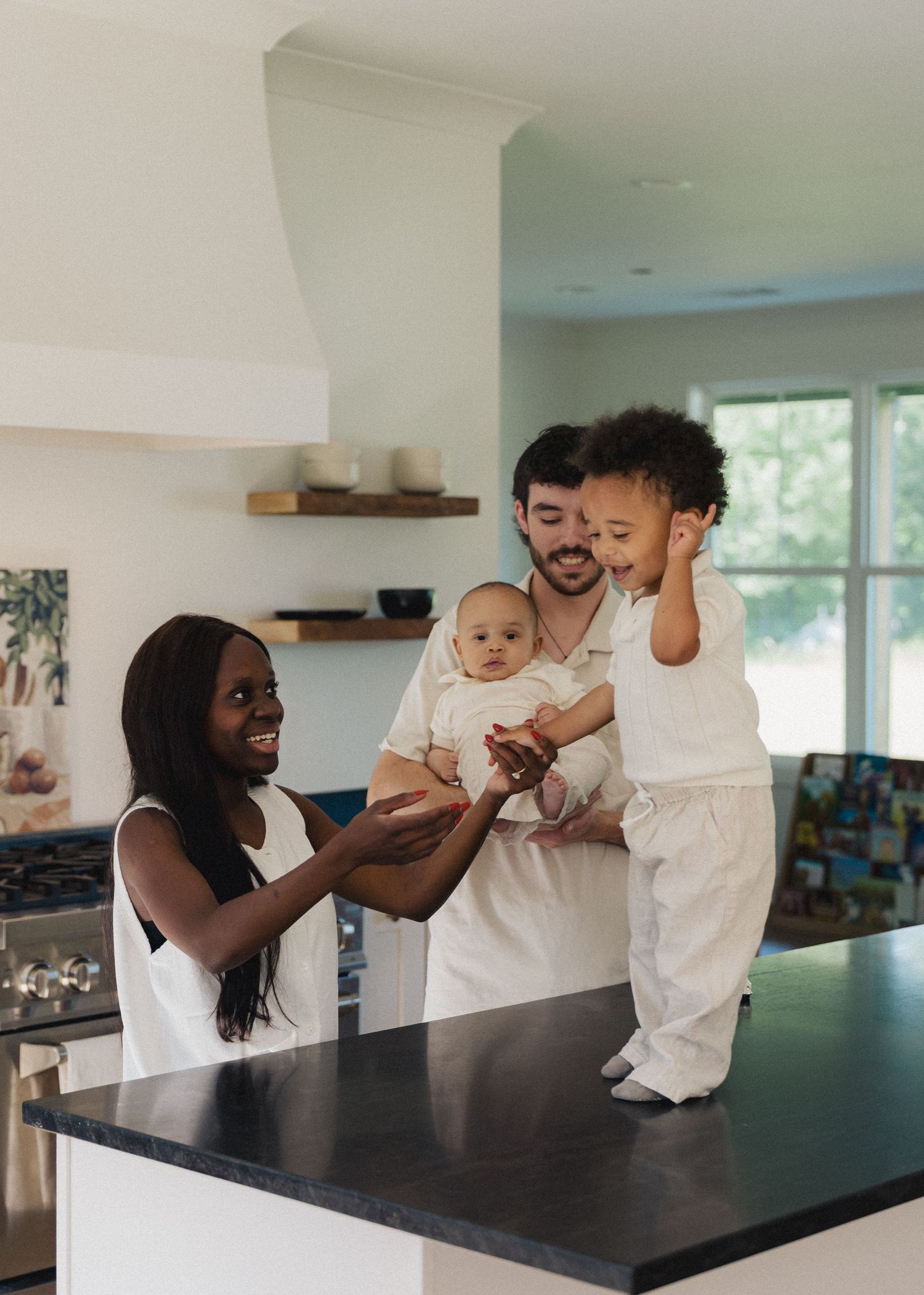 A happy interracial family with two children shares a joyful moment in a bright kitchen.