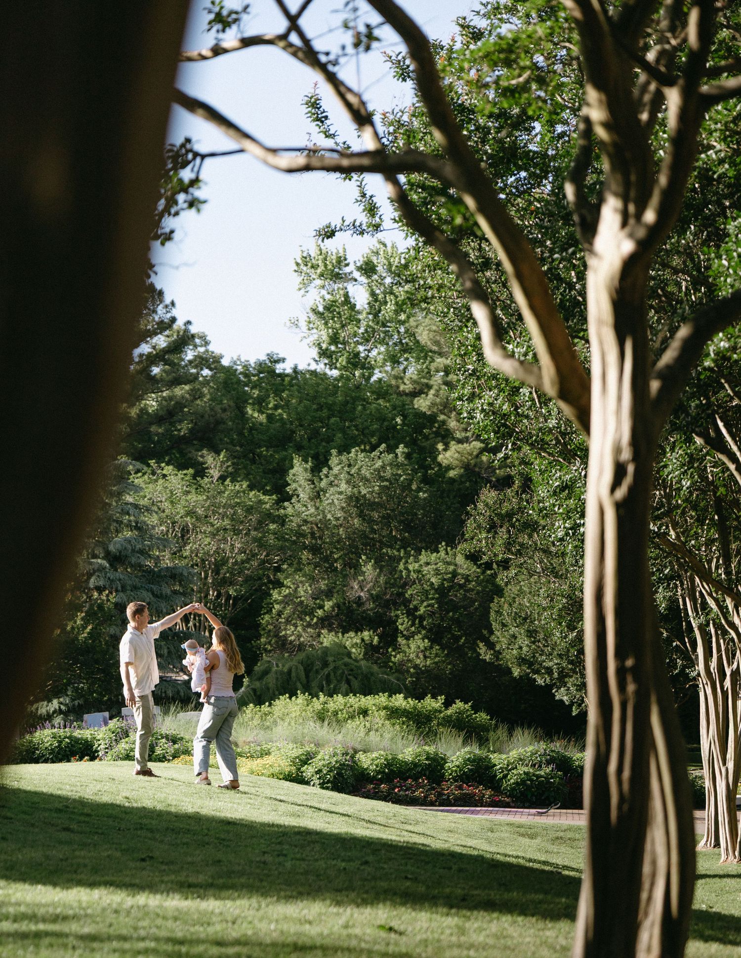 A couple dances together on a lush green lawn surrounded by trees.