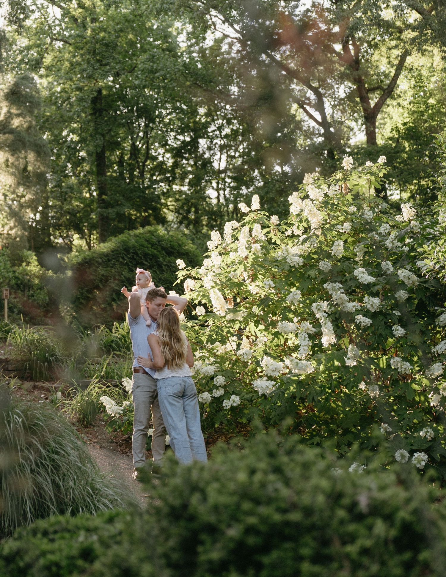 A couple dances together on a garden path surrounded by blooming white flowers.