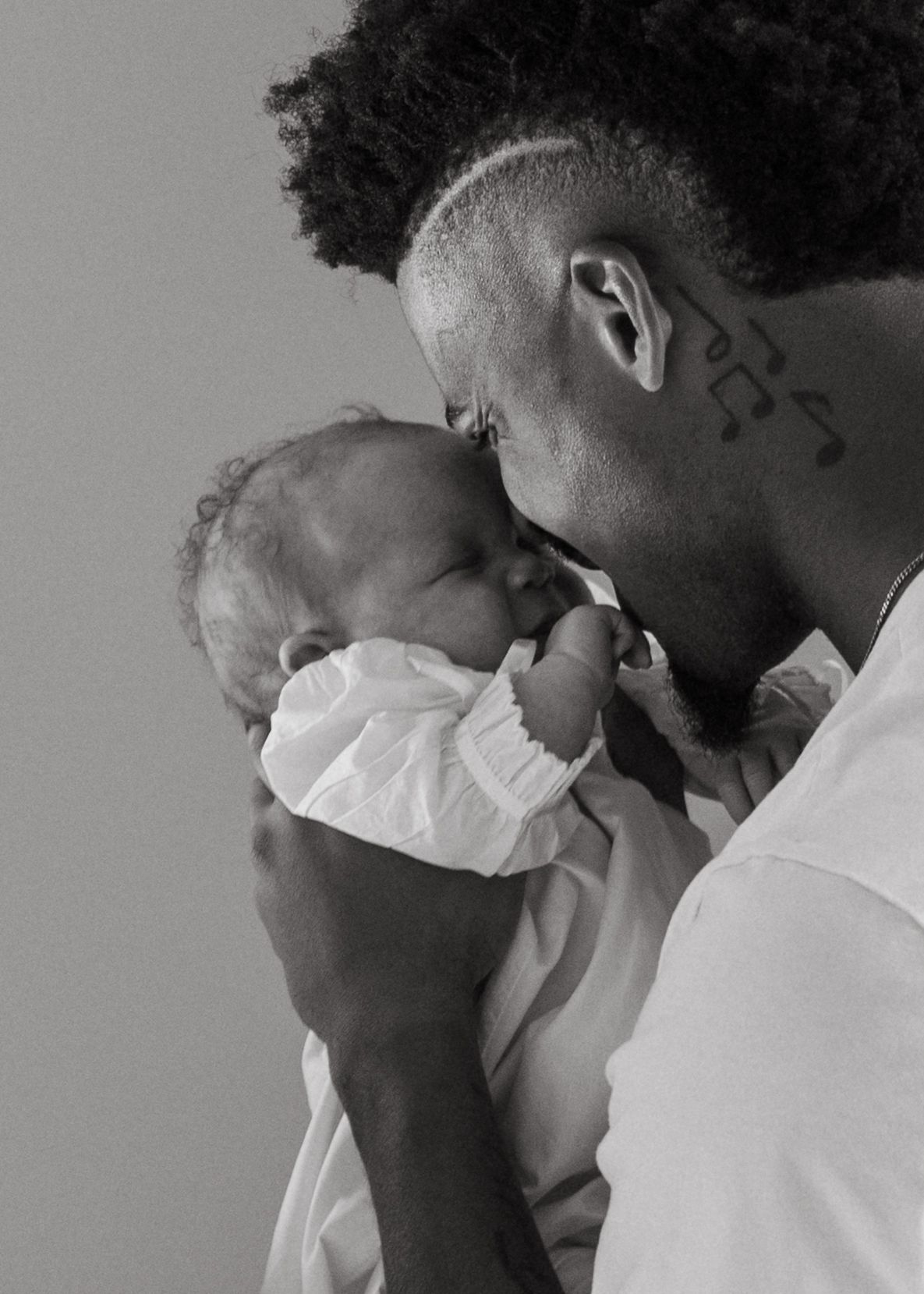 Black and white photo of a father kissing his newborn baby.