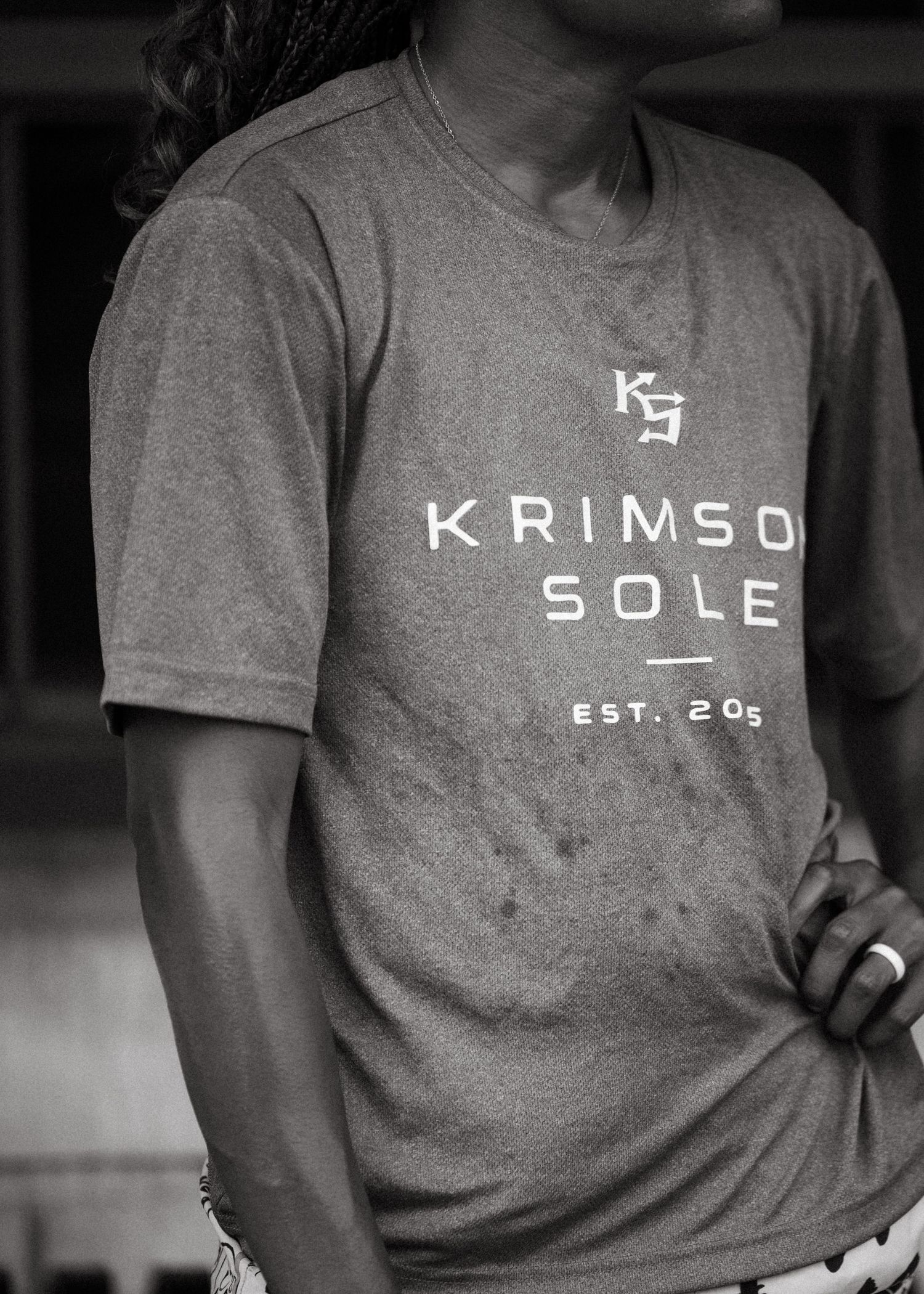 Close-up black and white photo of a Krimson Sole EST. 2005 gray branded t-shirt.