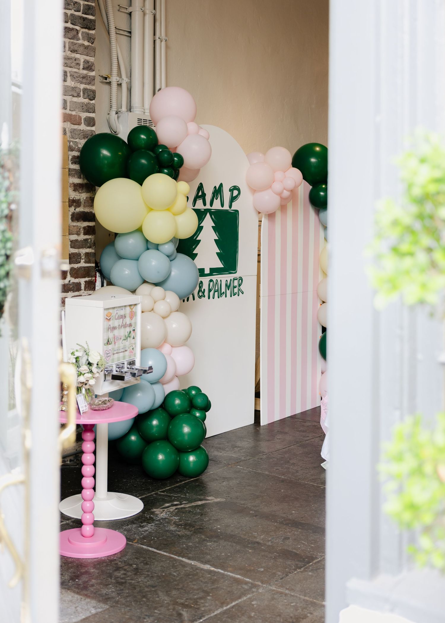 Camp Pippa and Palmer birthday party entrance decorated with colorful balloon garland arch.