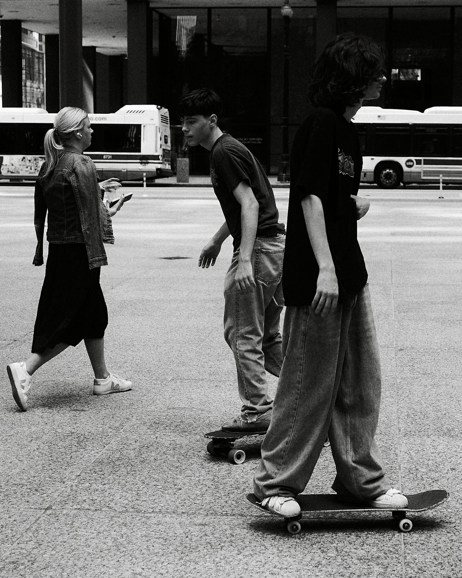 Two skateboarders riding on a city sidewalk in black and white street photography.