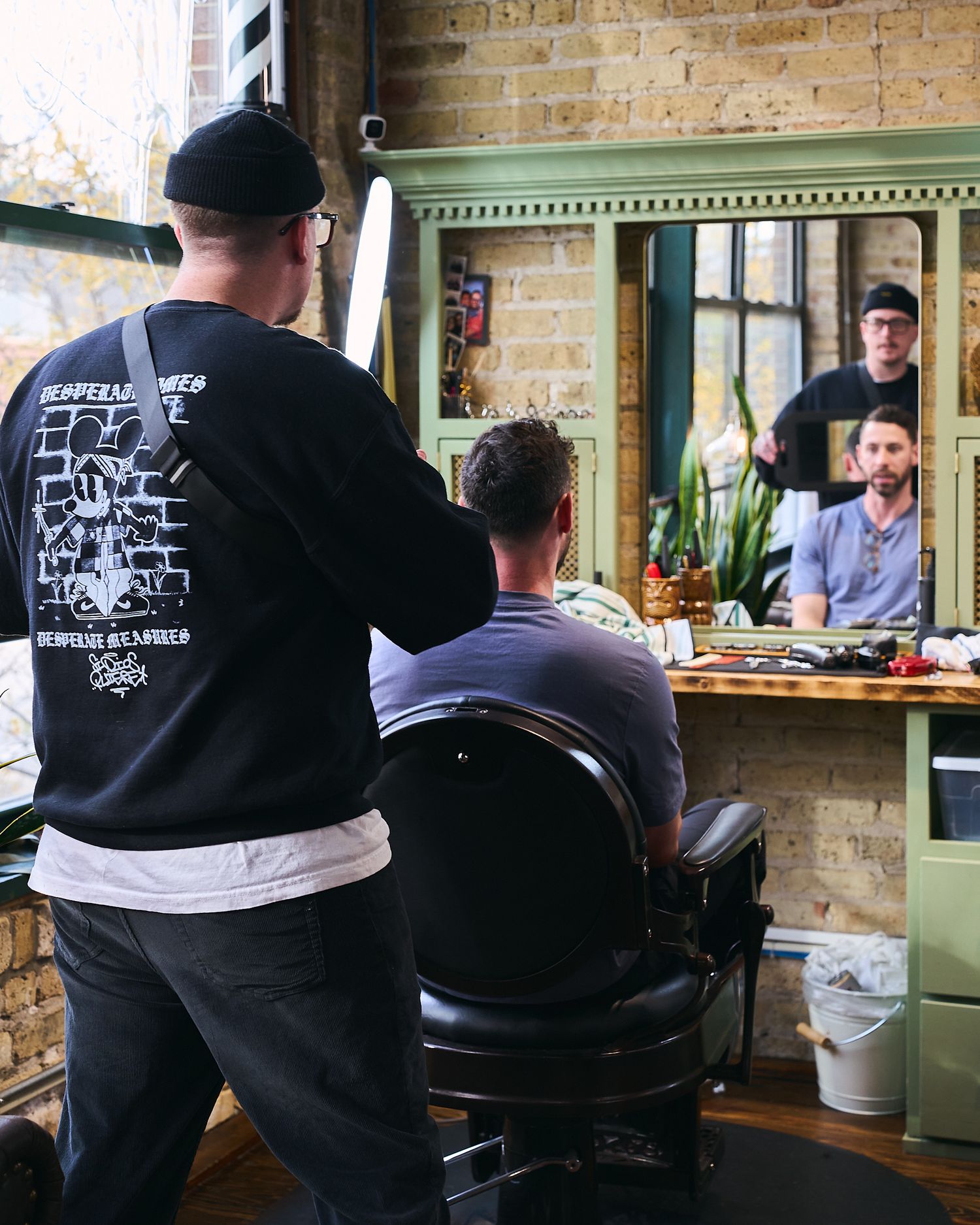 Barber cutting a clients hair viewed from behind in a classic barbershop mirror.