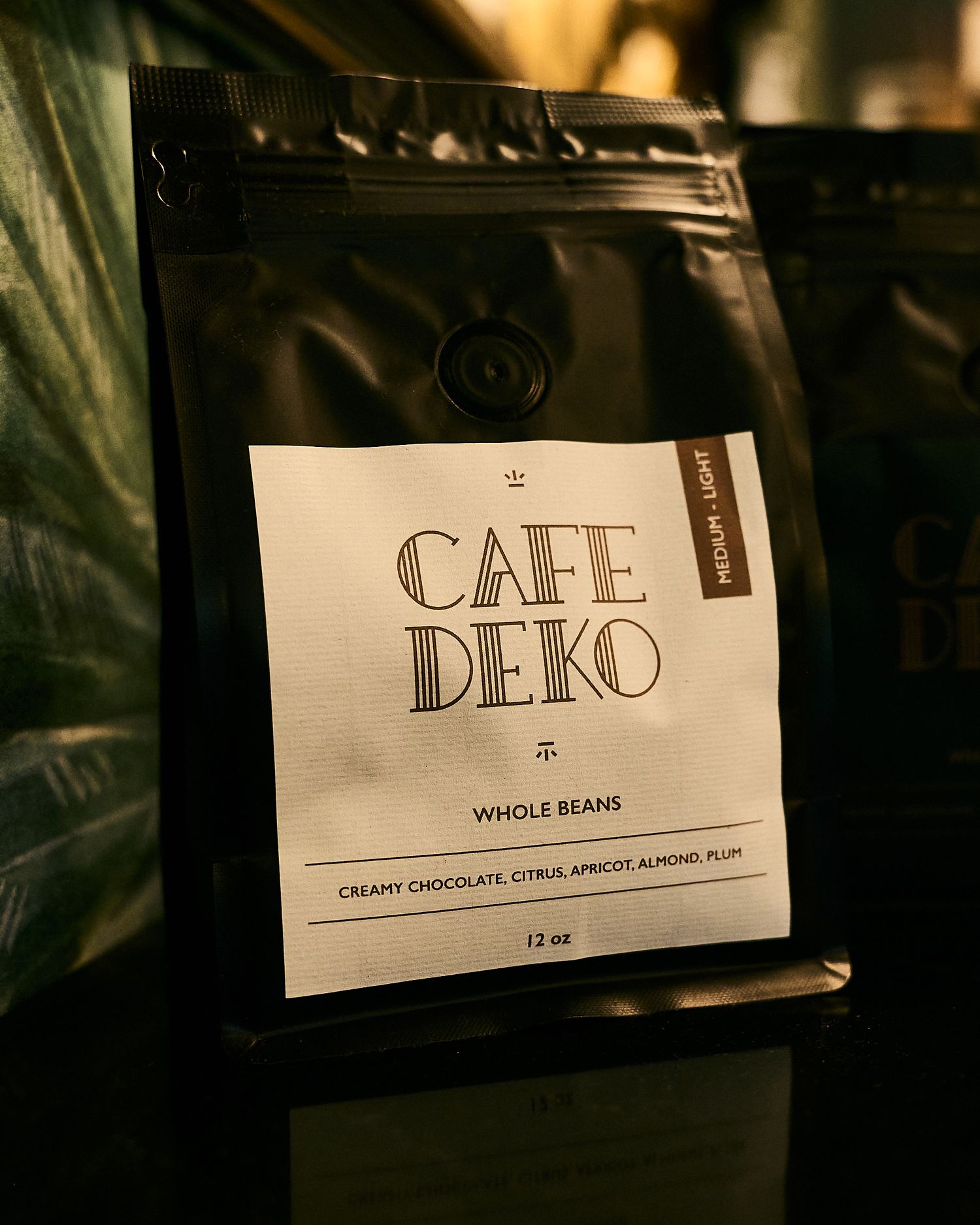 Cafe Deko whole bean coffee bag, medium-light roast with notes of creamy chocolate, citrus, apricot, almond, and plum.