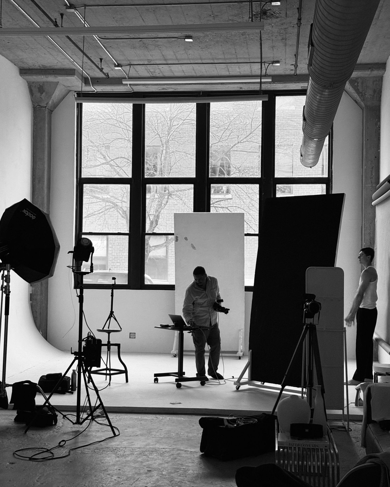 Black and white photo of a professional photography studio setup with lighting equipment and backdrop.