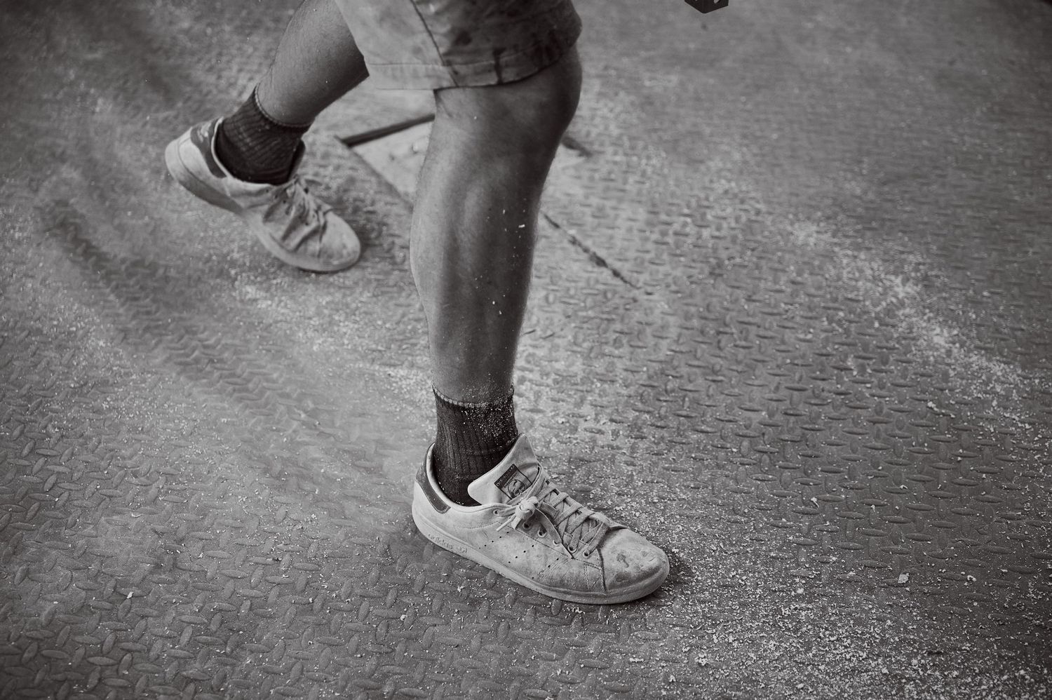 Close-up of dust-covered sneakers and legs standing on a foam-dusted workshop floor.