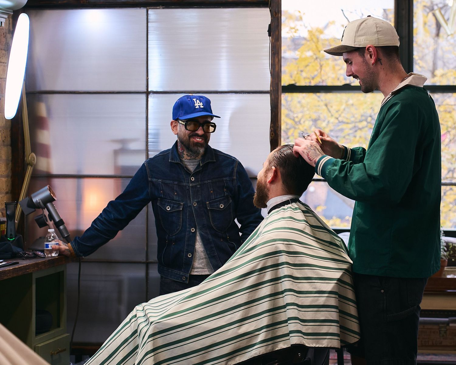 Two barbers working together on a clients haircut in a classic barbershop setting.
