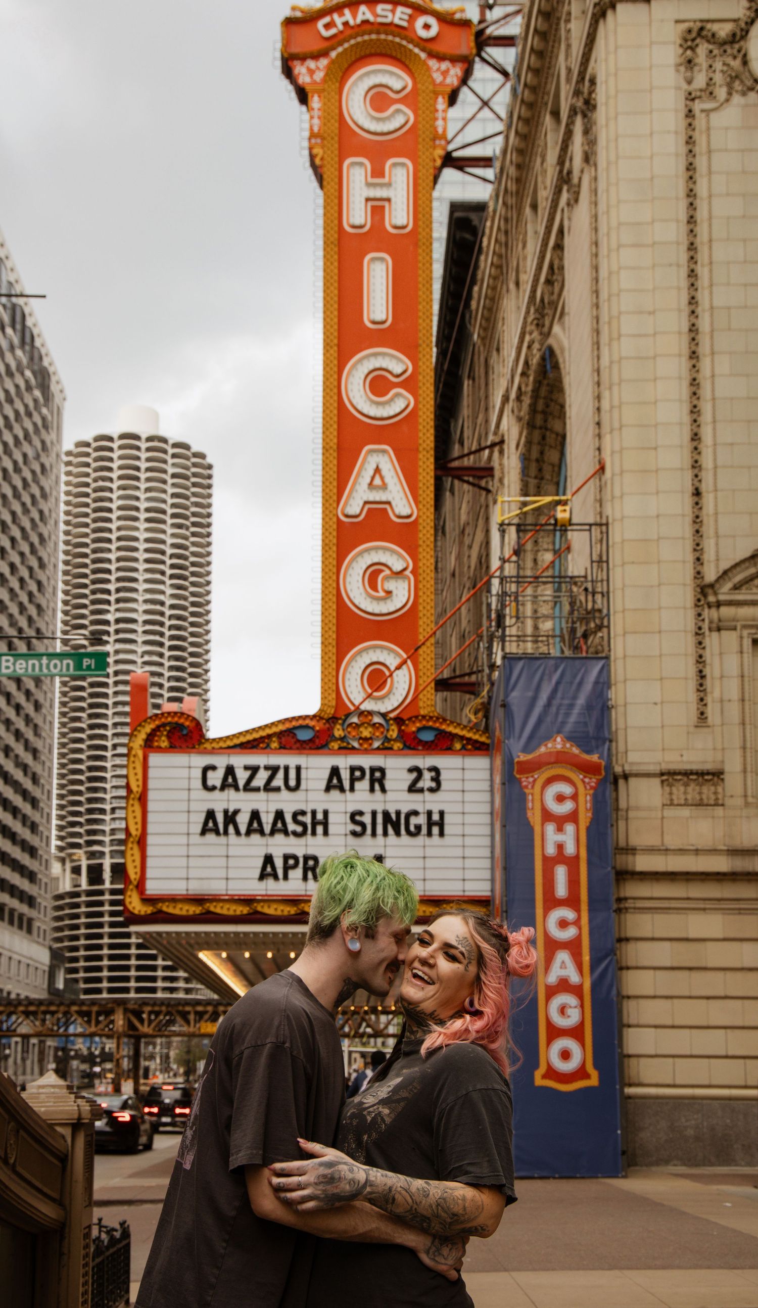 Couple embracing and kissing in front of the iconic Chicago Theatre marquee sign on State Street.