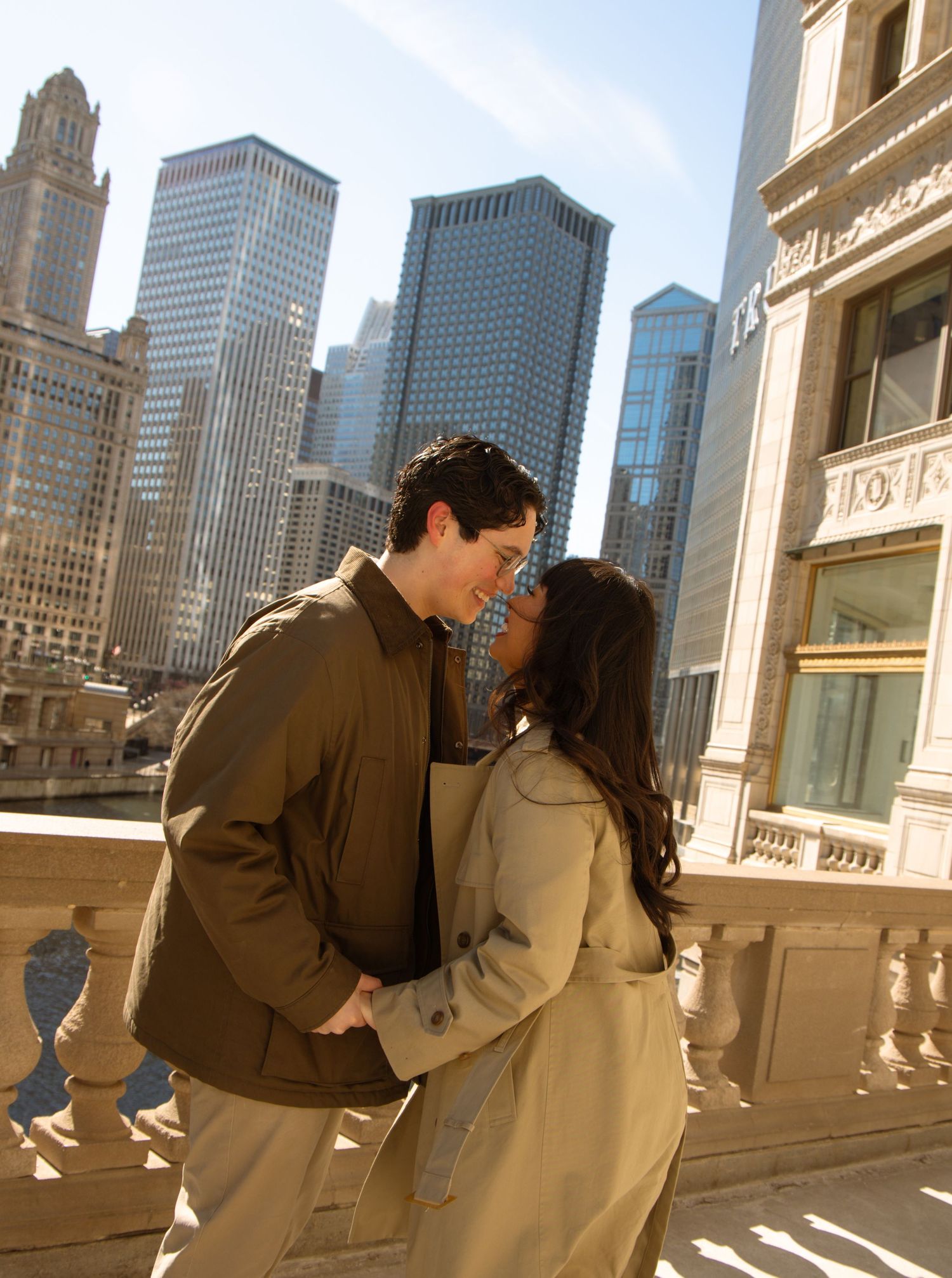 Romantic couple nearly kissing on a bridge with Chicago skyscrapers in sunny background.