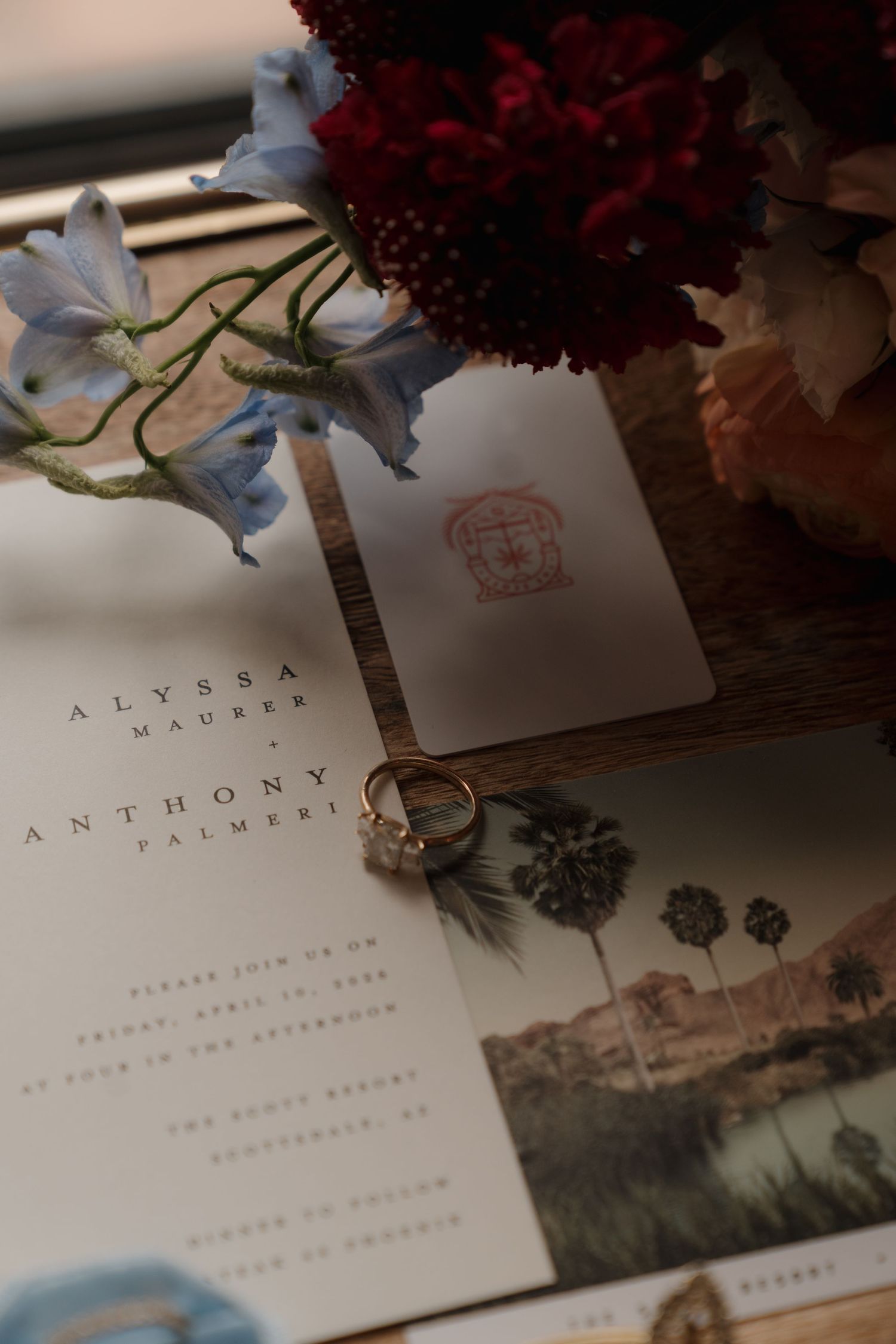 Wedding invitation suite for Alyssa Maurer and Anthony Palmeri with gold ring and floral arrangement.