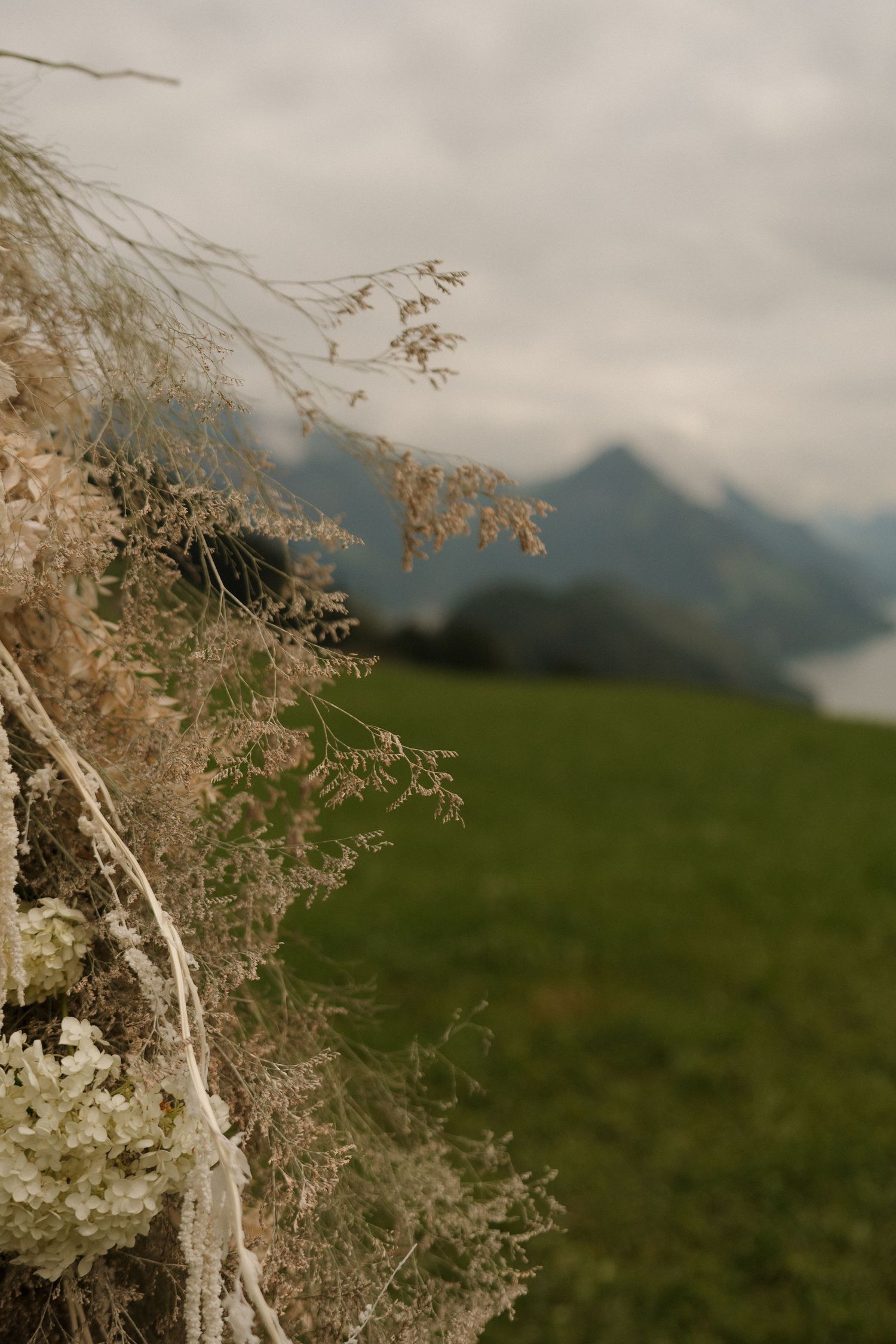 Close-up of dried wildflowers and white blooms arranged for an outdoor wedding ceremony with mountain backdrop.