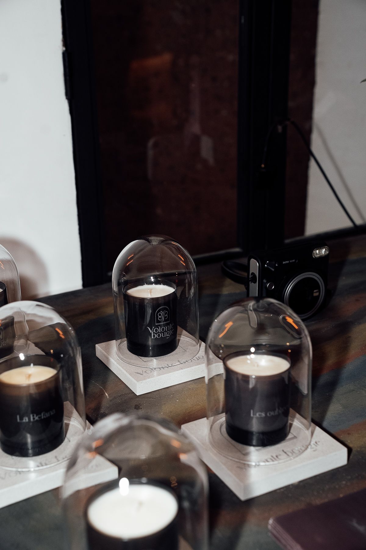 Luxury scented candles displayed under glass domes on a marble surface at an upscale event.