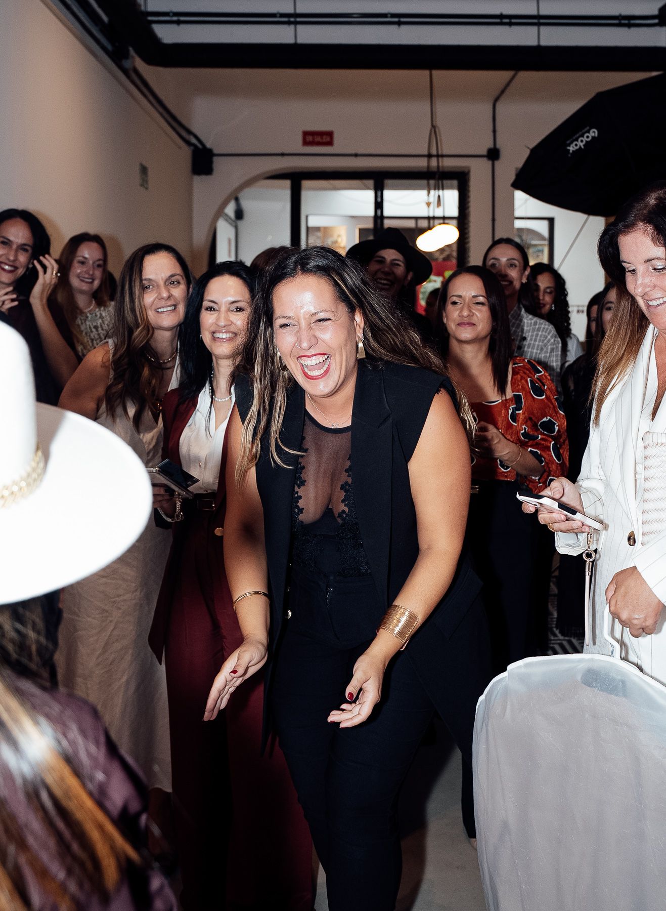 Crowd of smiling women gathered at an elegant indoor social event or fashion gathering.