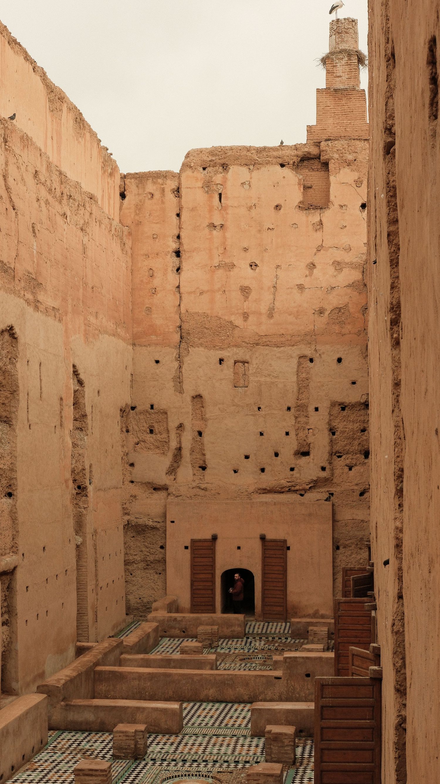 Ancient ruins of El Badi Palace in Marrakech, Morocco, featuring weathered sandstone walls and ornate tilework courtyard.