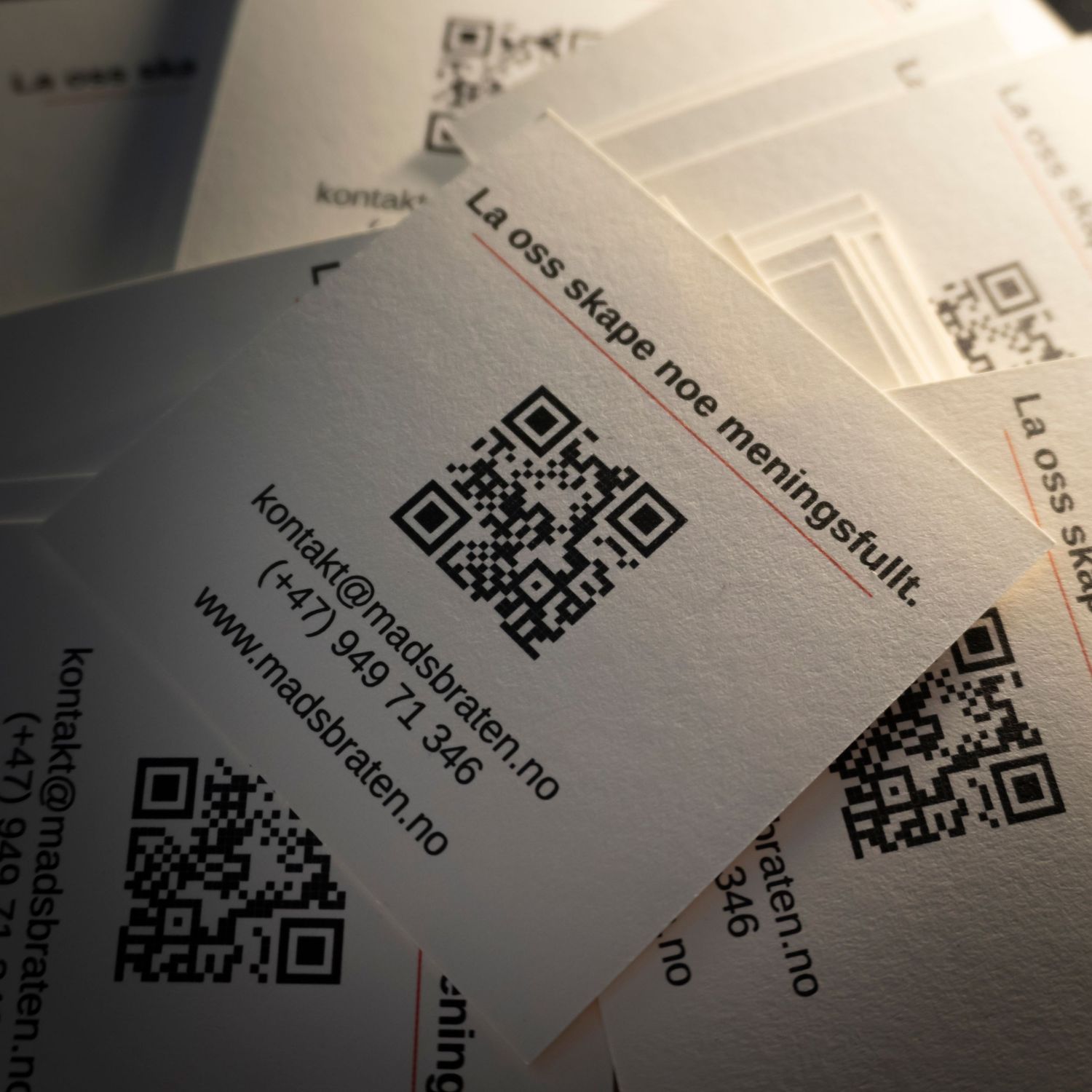 Stack of business cards with QR codes and Norwegian text for Madsbraten.no, displaying contact details and slogan.