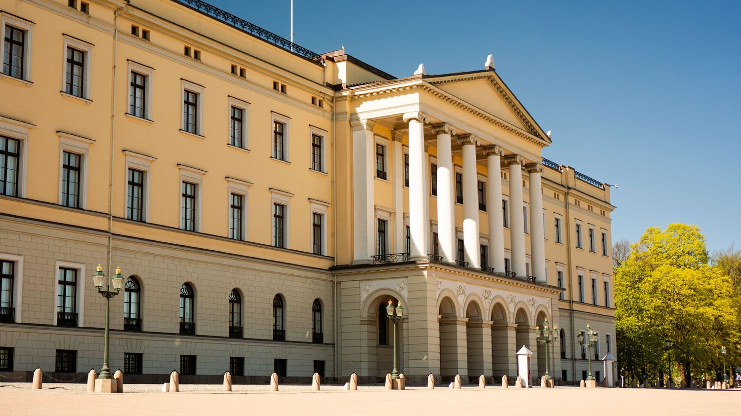 Neoclassical facade of the Royal Palace in Oslo, Norway, on a sunny day with blue skies.