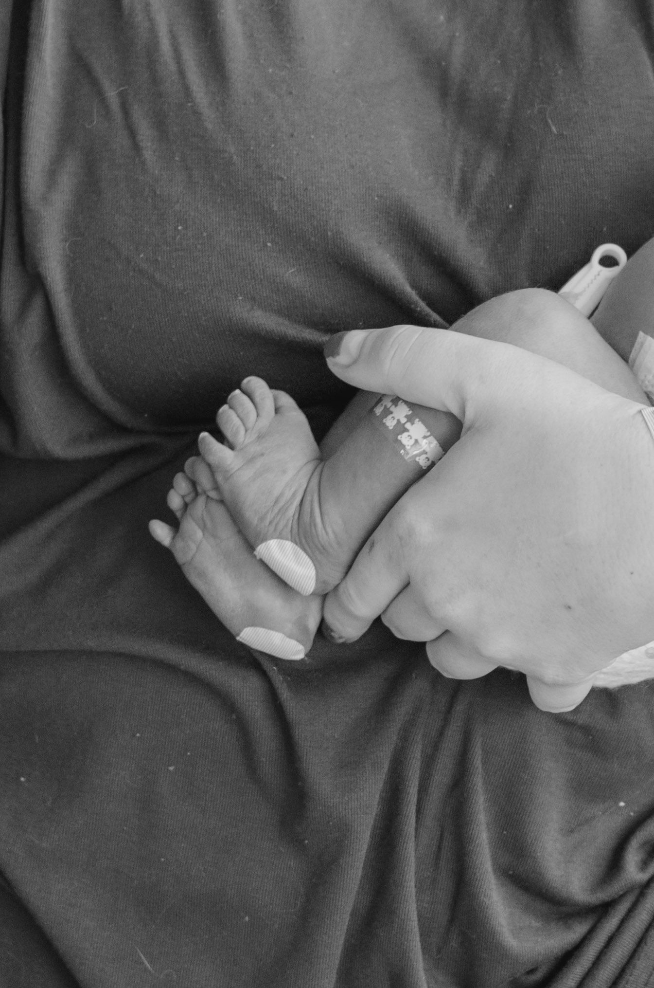 Close-up of tiny newborn baby feet held gently in mother's hands