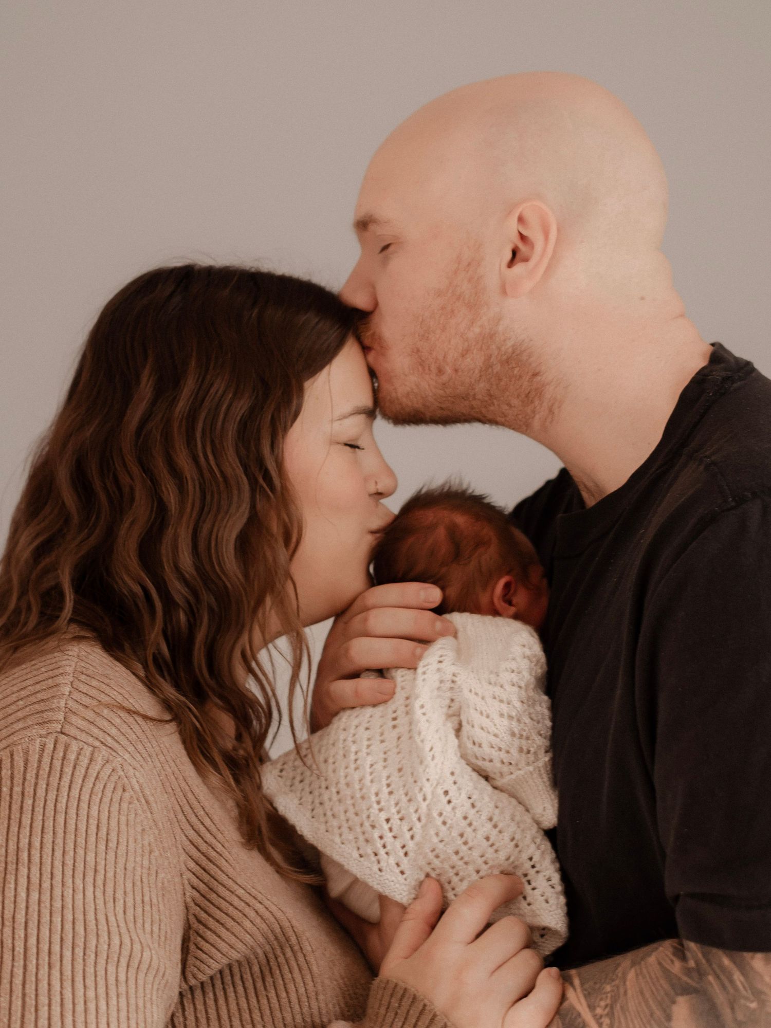 Mother and Father holding newborn during in-home session in Saskatoon