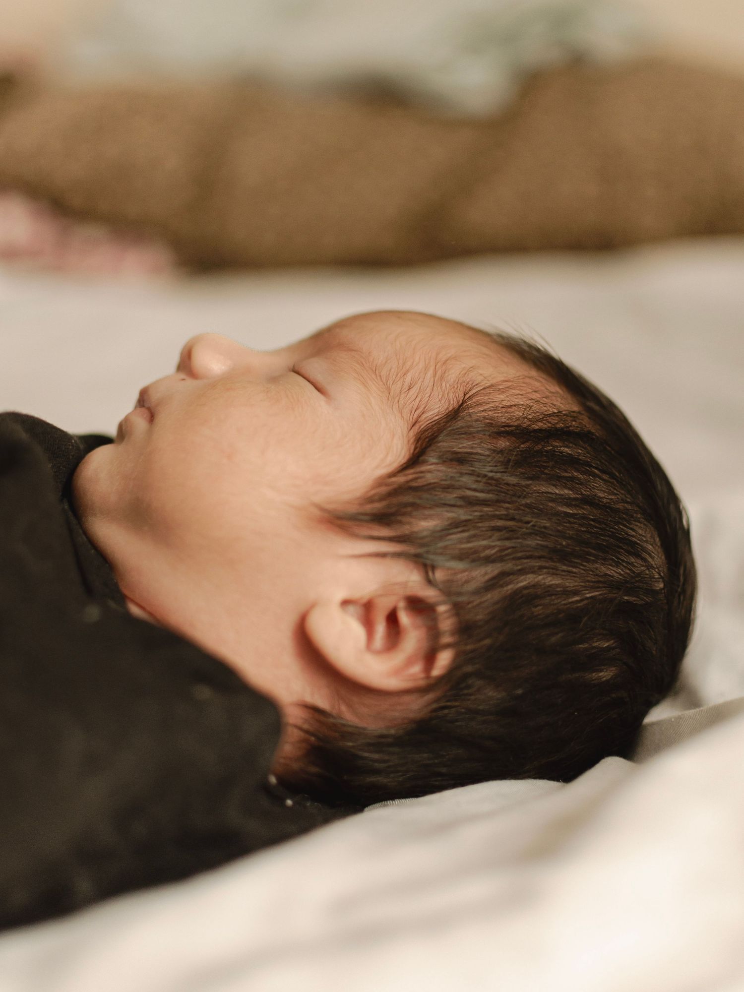 Lifestyle newborn session in a calm home setting with warm earthy tones