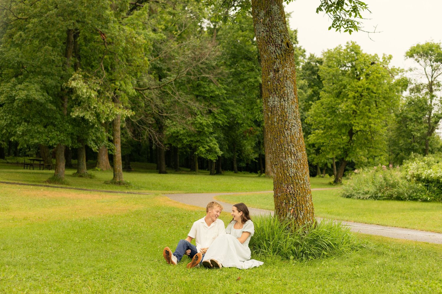 Couple sitting under a tree during their rainy session at Lake Carlos State Park in Alexandria, Minnesota.