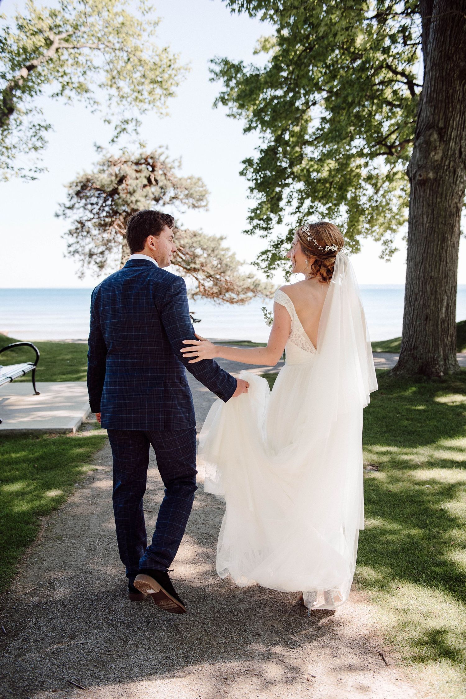 A bride and groom looking at each other as they walk towards the lake at Paletta Mansion