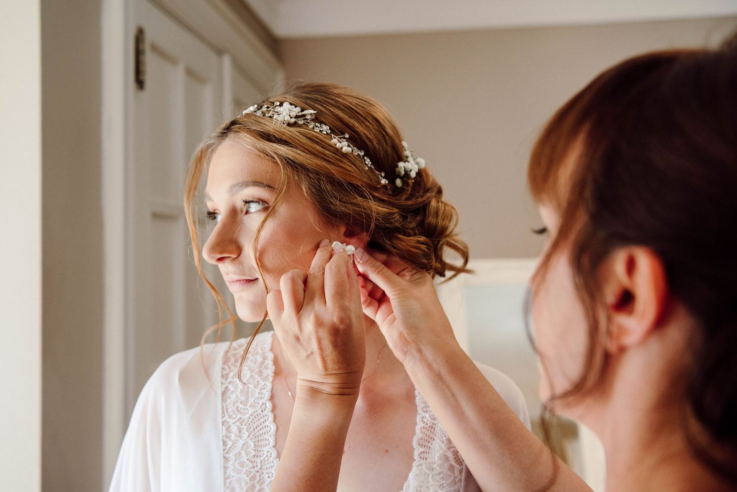 The bride's mother helping her put on her wedding earrings at Paletta Mansion