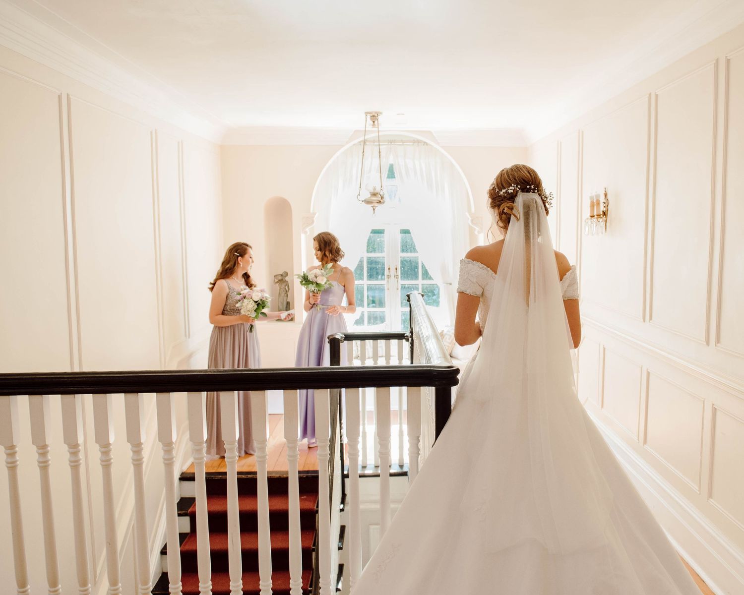 The back of the bride and her bridesmaids as they prepare to walk downstairs at Paletta Mansion