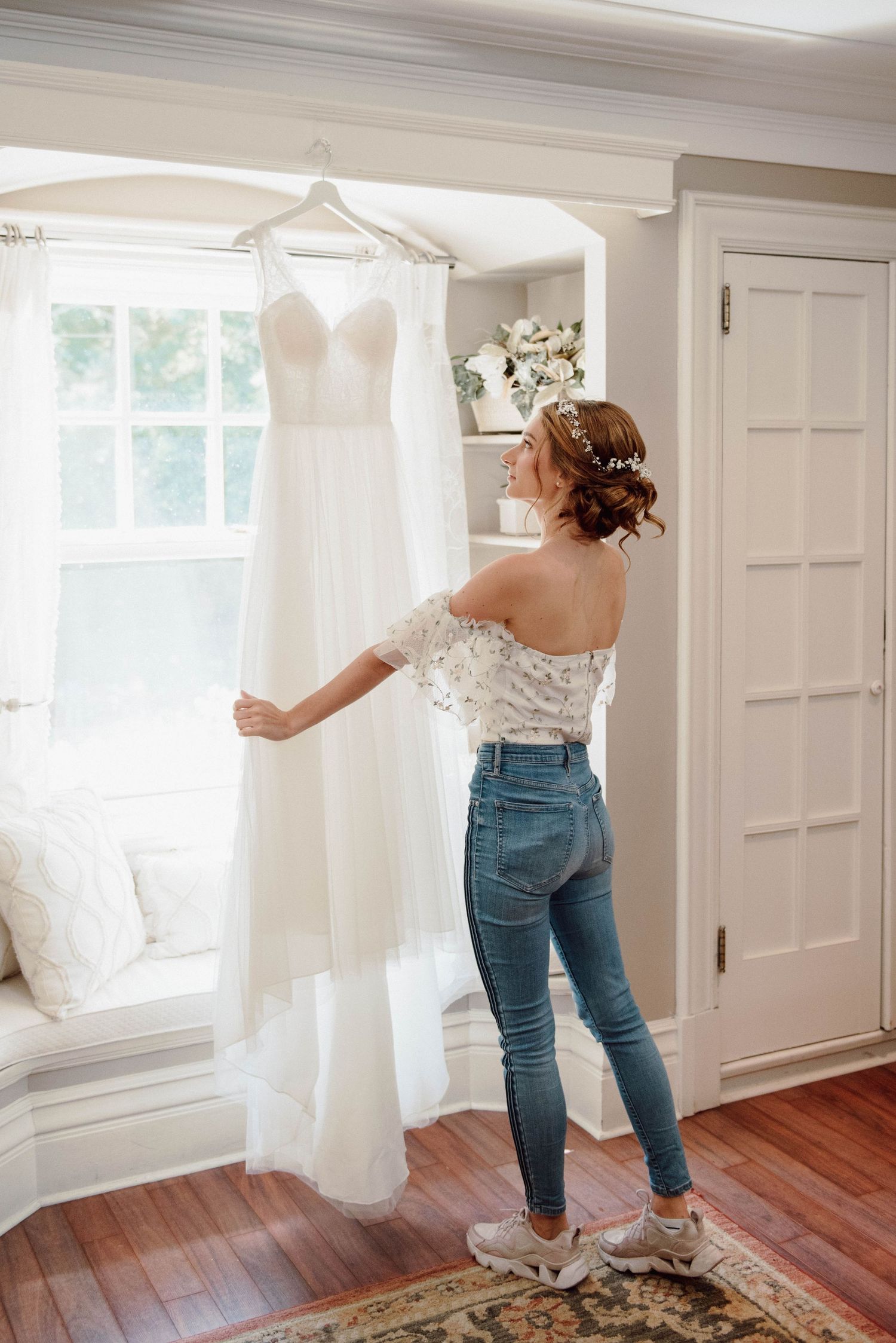 A bride looks up at her wedding dress as it is hanging at Paletta Mansion