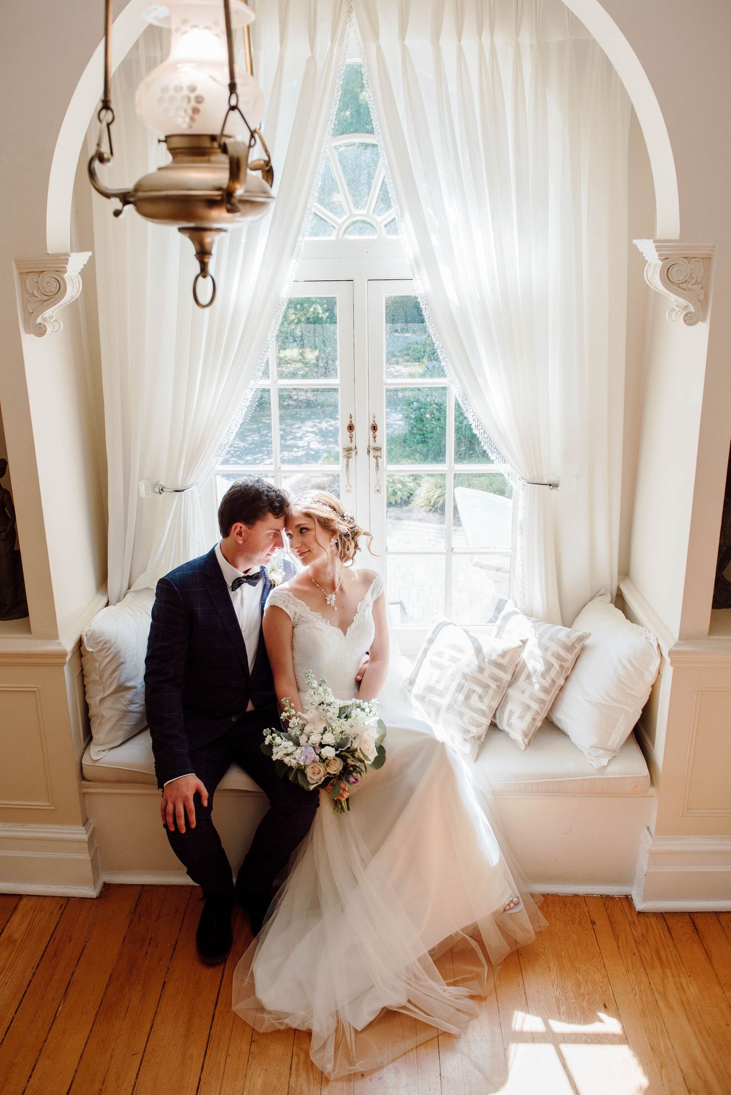 The bride and groom sitting on a window seat at Paletta Mansion