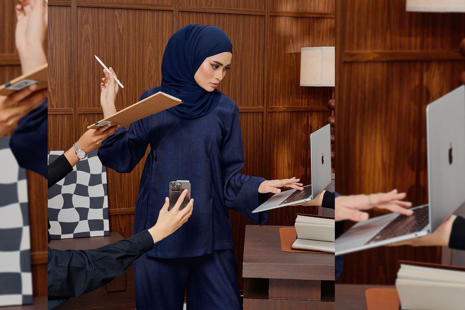 Professional woman in navy hijab and matching suit multitasking in a modern office environment.