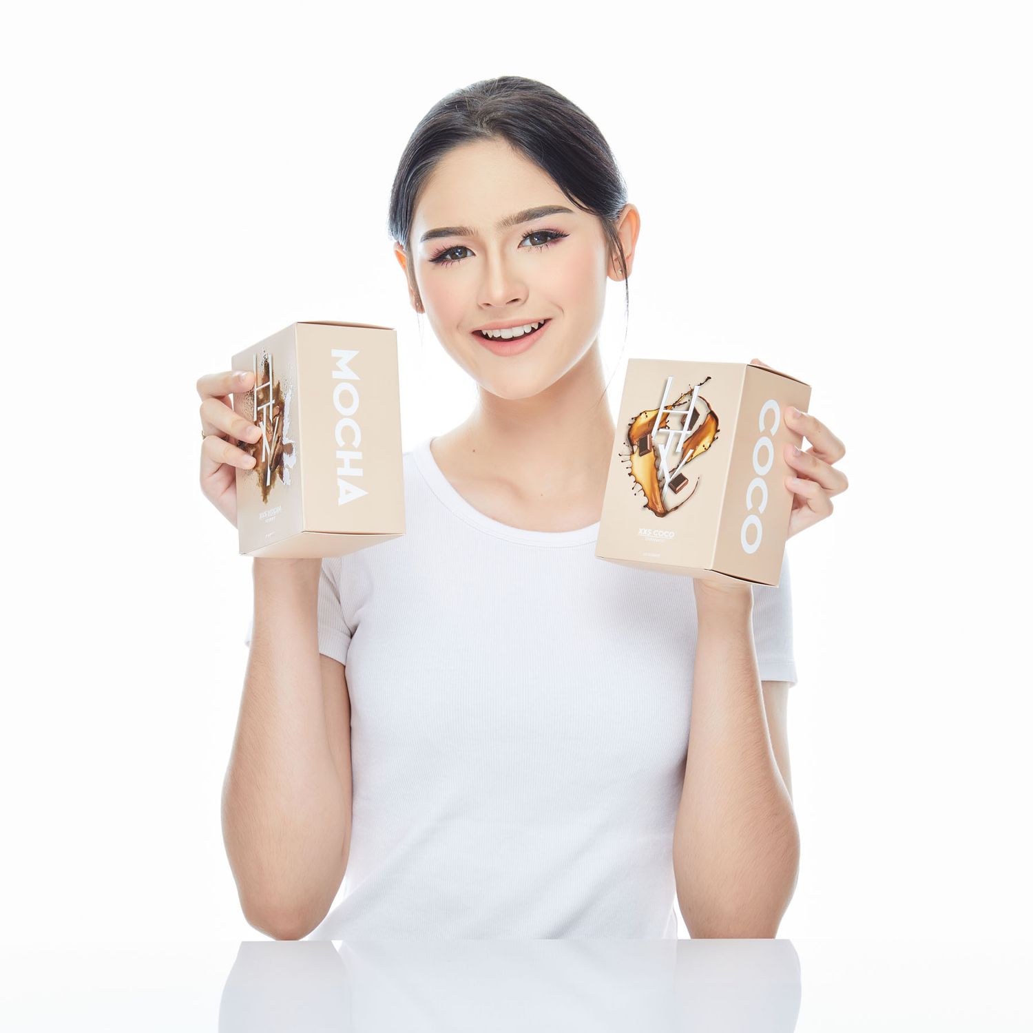 Smiling woman in white t-shirt holding two kraft paper boxes labeled Mocha and Coco on white background.