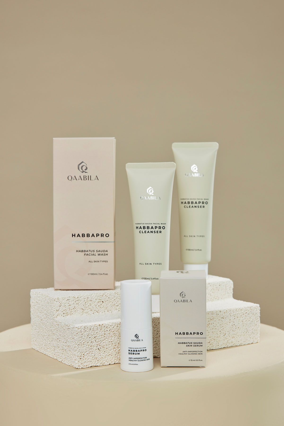 Qaabila HabbaPro skincare collection displayed on white textured pedestals including cleanser and facial wash.