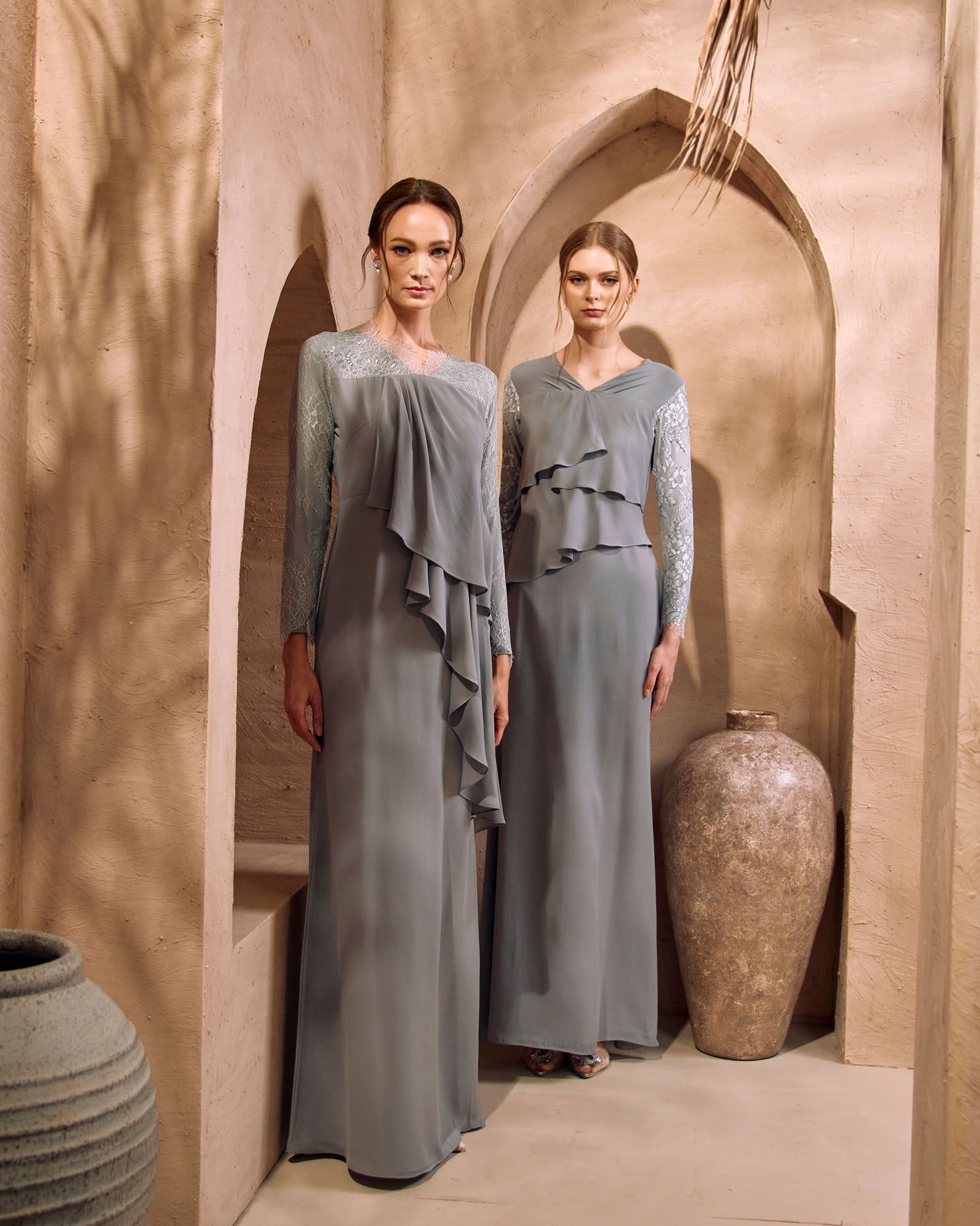 Two women in matching sage grey modest dresses with lace and ruffle details in desert setting.