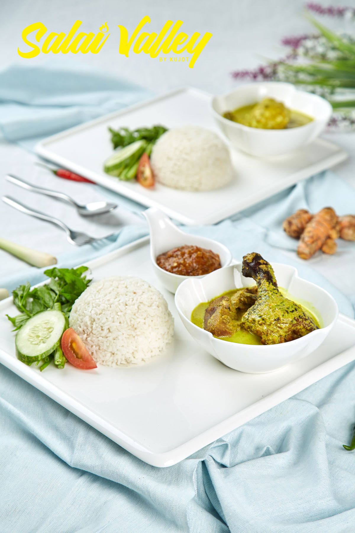 Two plates of rice with green curry chicken, sambal, and fresh vegetables from Sulai Valley restaurant.