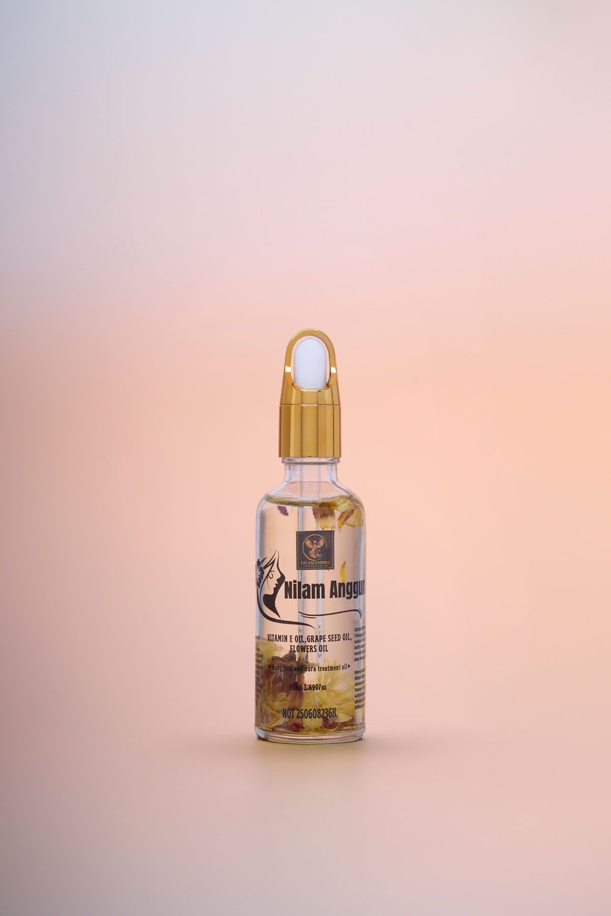 Single Hilam Anggun vitamin E facial serum dropper bottle with gold cap on a soft pink gradient background.