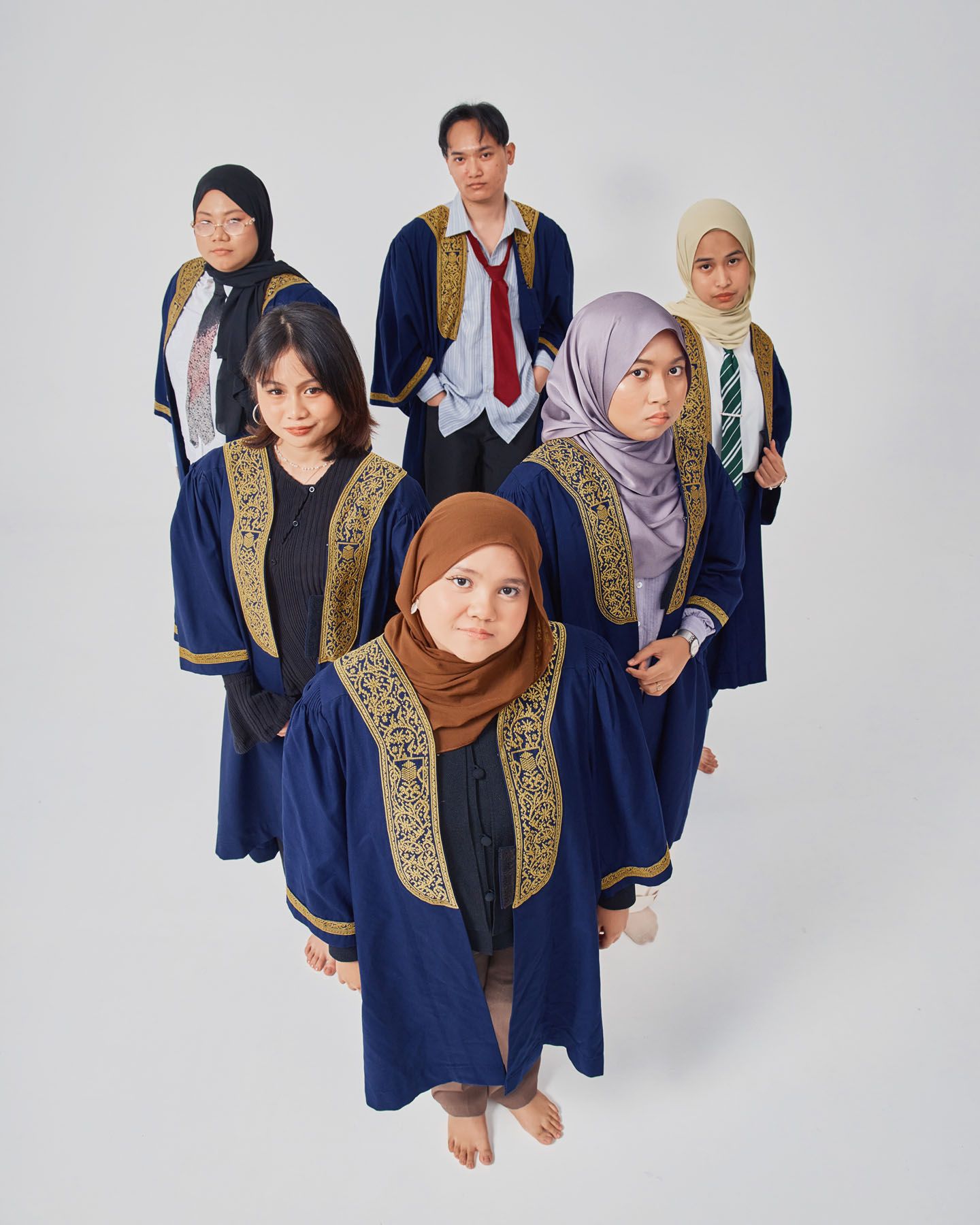 Six students in navy graduation robes photographed from above in a creative aerial group shot.