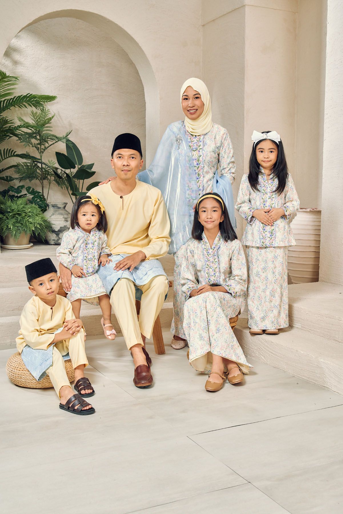 Malaysian Muslim family of six in pastel blue and gold traditional Eid outfits posing together.